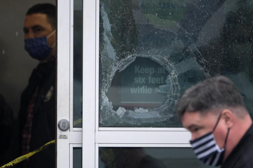 Police officers work near a broken glass door at the scene where two people were struck by gunfire in a shooting at a Burlington store — part of a chain formerly known as Burlington Coat Factory in North Hollywood, Calif., Thursday.