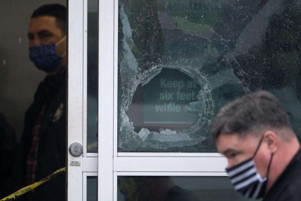 Police officers work near a broken glass door at the scene where two people were struck by gunfire in a shooting at a Burlington store — part of a chain formerly known as Burlington Coat Factory in North Hollywood, Calif., Thursday.