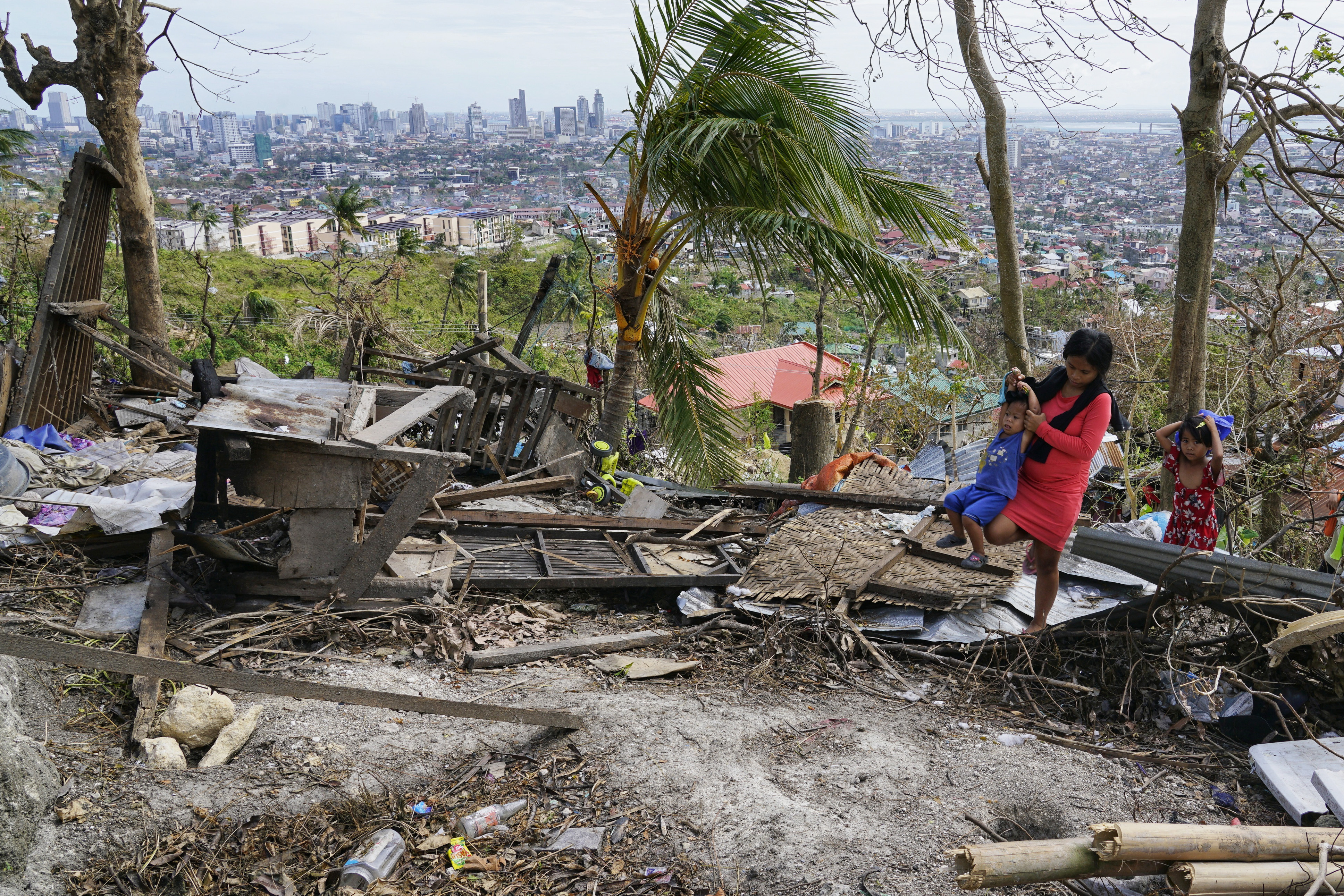Alona Nacua carries her son passing over debris from their damaged house due to Typhoon Rai in Cebu city, central Philippines on Christmas Day, Saturday, Dec. 25, 2021. Nacua said she and her husband managed to receive rice and four small cans of sardines and corned beef so they could feed their family Saturday. "It's the saddest Christmas for me, seeing my children suffer this way on this day," added Nacua, who is pregnant with her fourth child. 