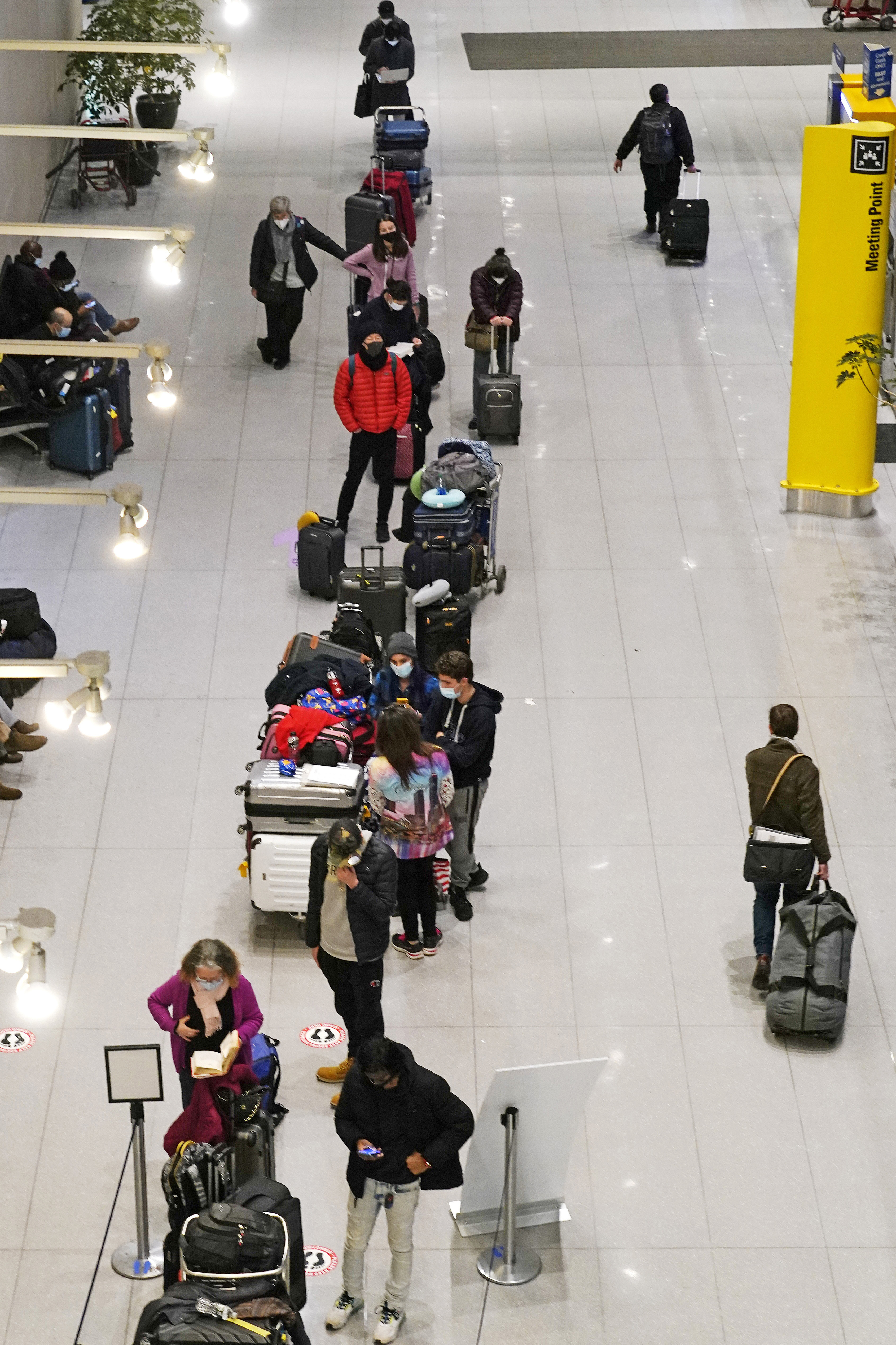 Travelers wait in line to be tested for COVID-19 at Logan Airport in Boston on Tuesday. Airlines continued to cancel hundreds of flights Saturday as staffing issues tied to COVID-19 disrupted holiday celebrations during one of the busiest travel times of the year.
