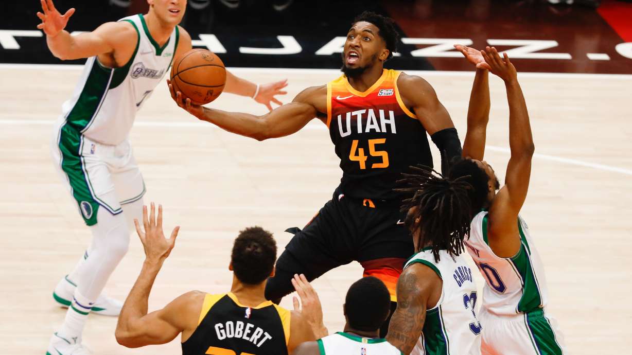 Utah Jazz guard Donovan Mitchell, center, attempts the score past Dallas Mavericks defenders during an NBA game at Vivint Arena in Salt Lake City on Saturday, Dec. 25, 2021.