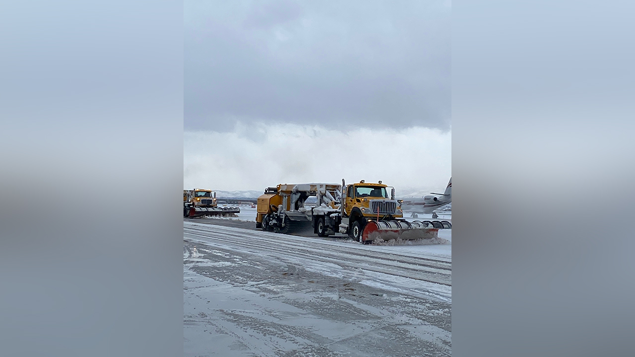 Plows work to clear runways at Salt Lake City International Airport Sunday.