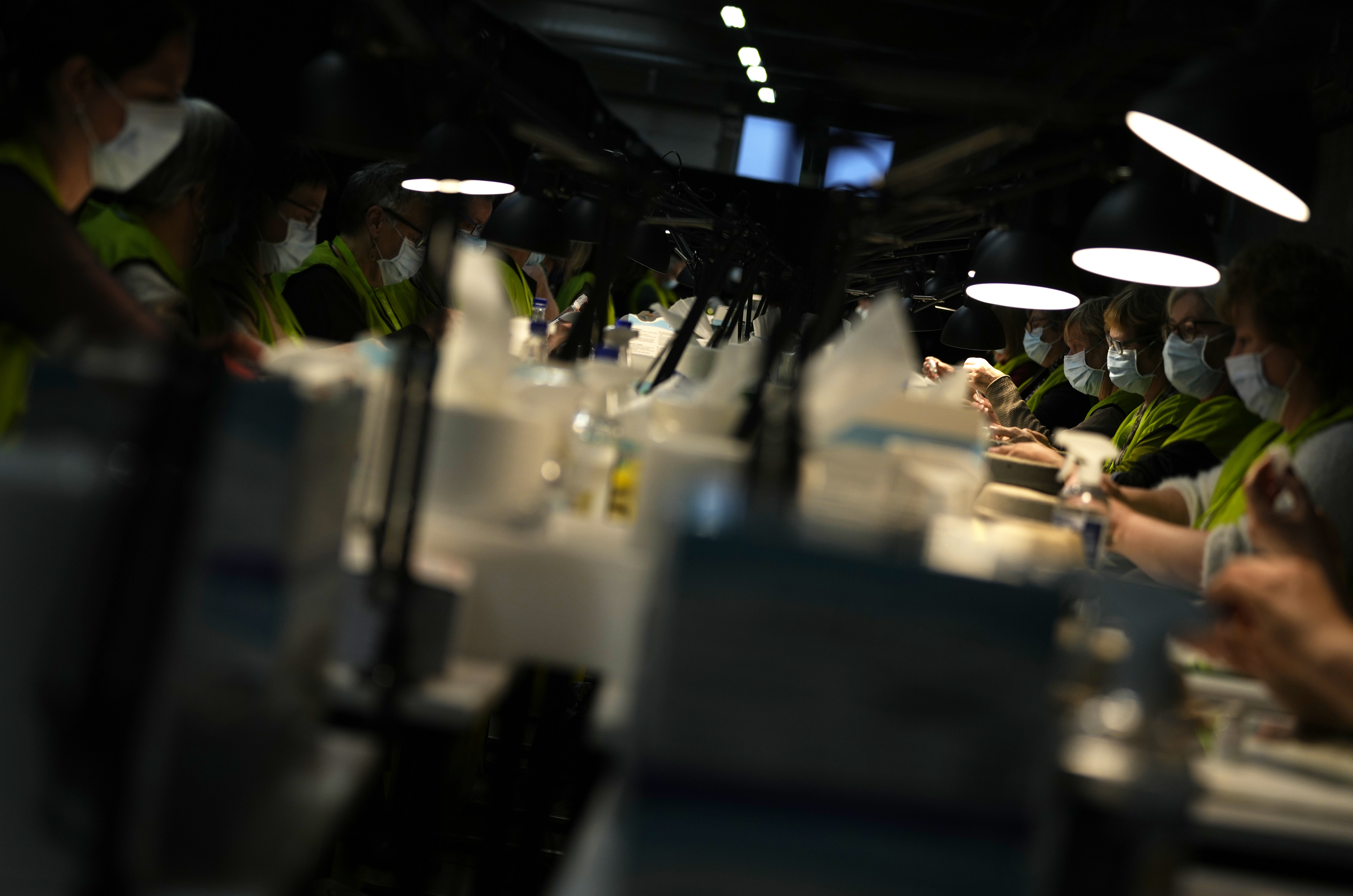 Pharmacists fill syringes from vials of the Moderna booster vaccine at the Antwerp Expo vaccine center in Antwerp, Belgium on Monday. In Belgium, many flocked to their local vaccine center to receive their booster shots and stay ahead of the surging omicron infections. 