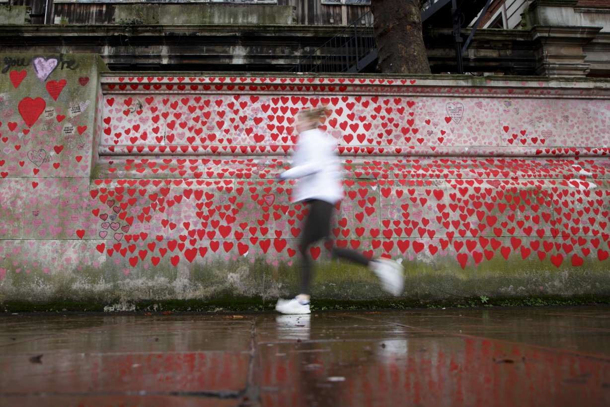 A woman jogs alongside the National Covid Memorial Wall in London, Monday. In Britain, where the omicron variant has been dominant for days, government requirements have been largely voluntary and milder than those on the continent, but the Conservative government said it could impose new restrictions after Christmas.