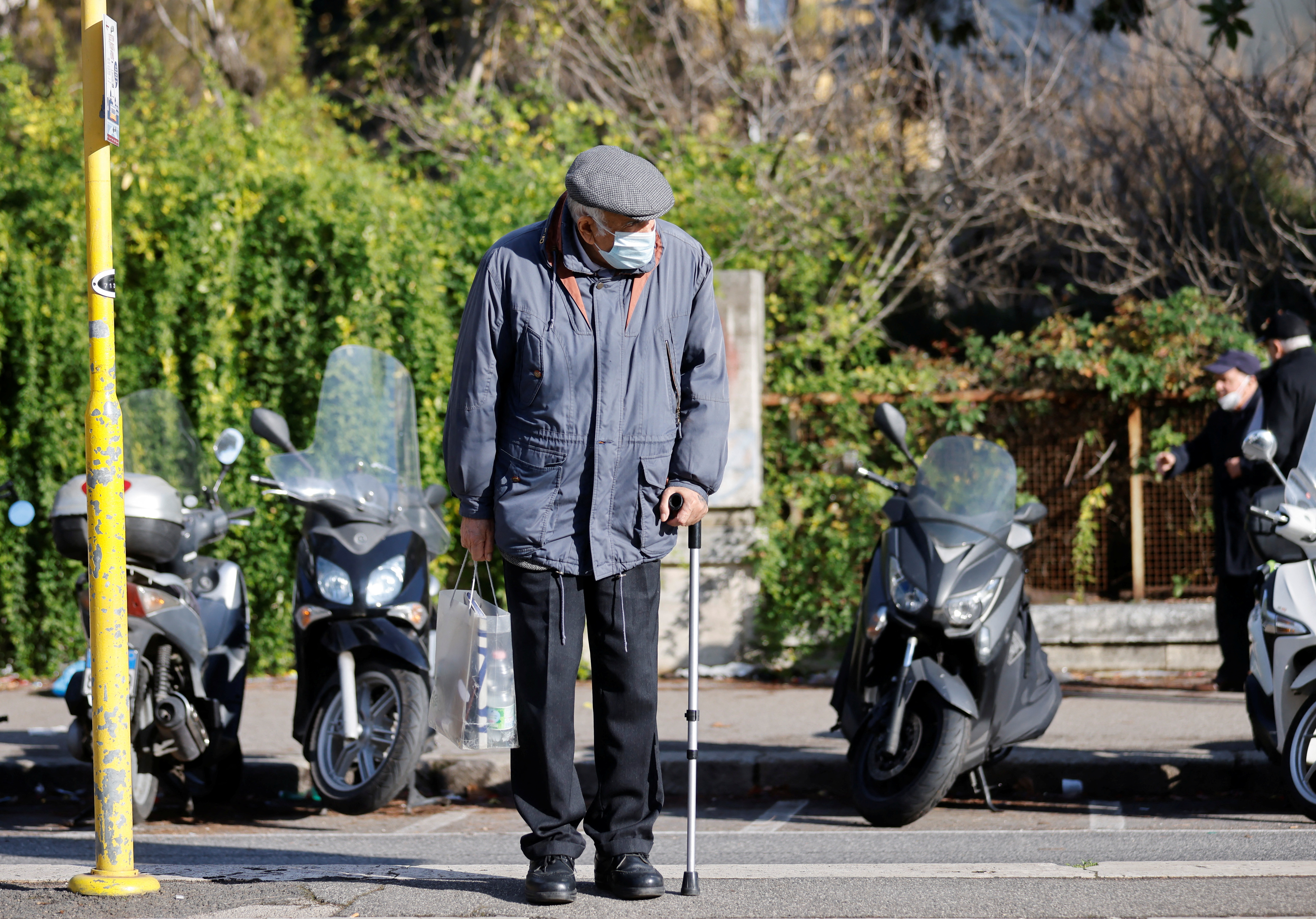 A man wearing a face mask waits for a tram as coronavirus disease cases rise and Christmas nears, in Rome, Italy, Thursday.