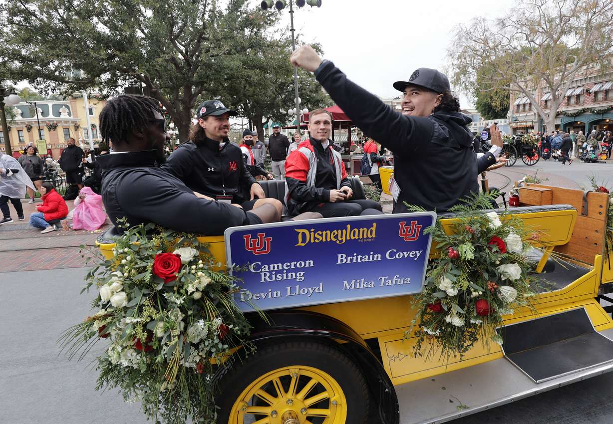 Utah Utes linebacker Devin Lloyd, Utah Utes quarterback Cameron Rising, Utah Utes wide receiver Britain Covey and Utah Utes defensive end Mika Tafua wave to fans during a parade at Disneyland in Anaheim, Calif., on Monday, Dec. 27, 2021, as part of events leading up to the Rose Bowl.