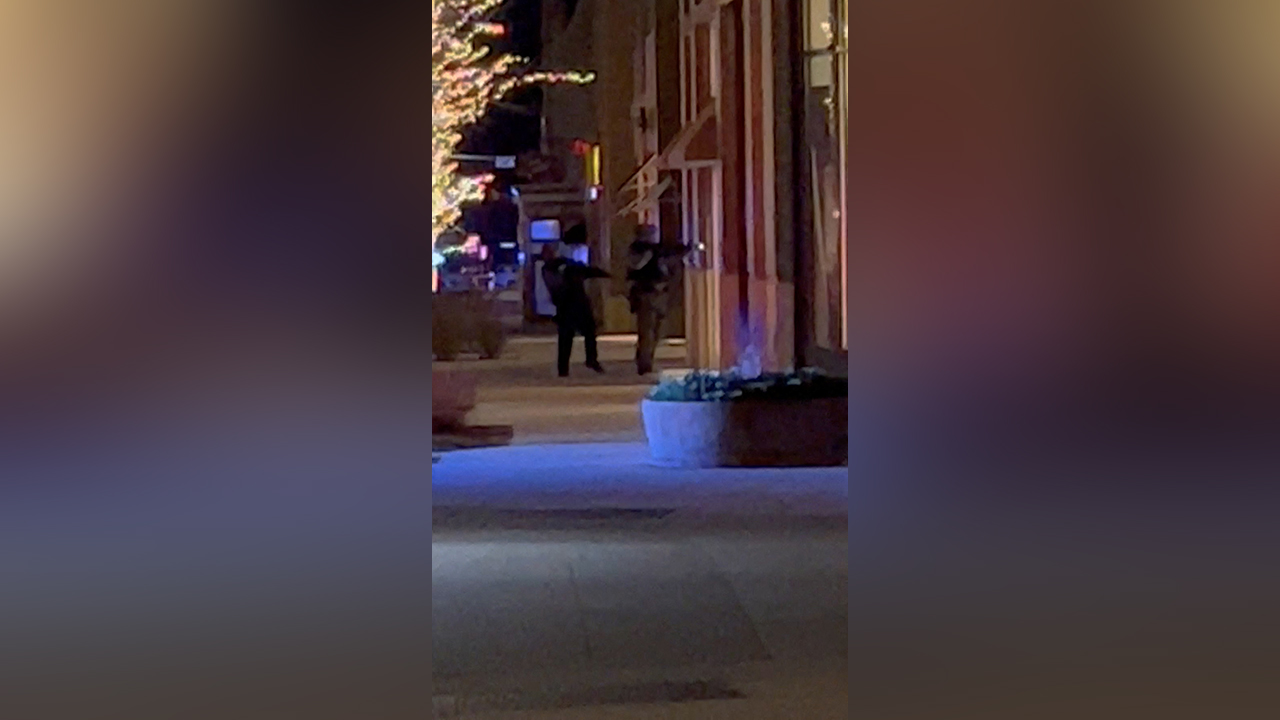 Armed officers stand outside a building in Lakewood, Colo., Monday.  A gunman killed four people and injured an officer, police said.