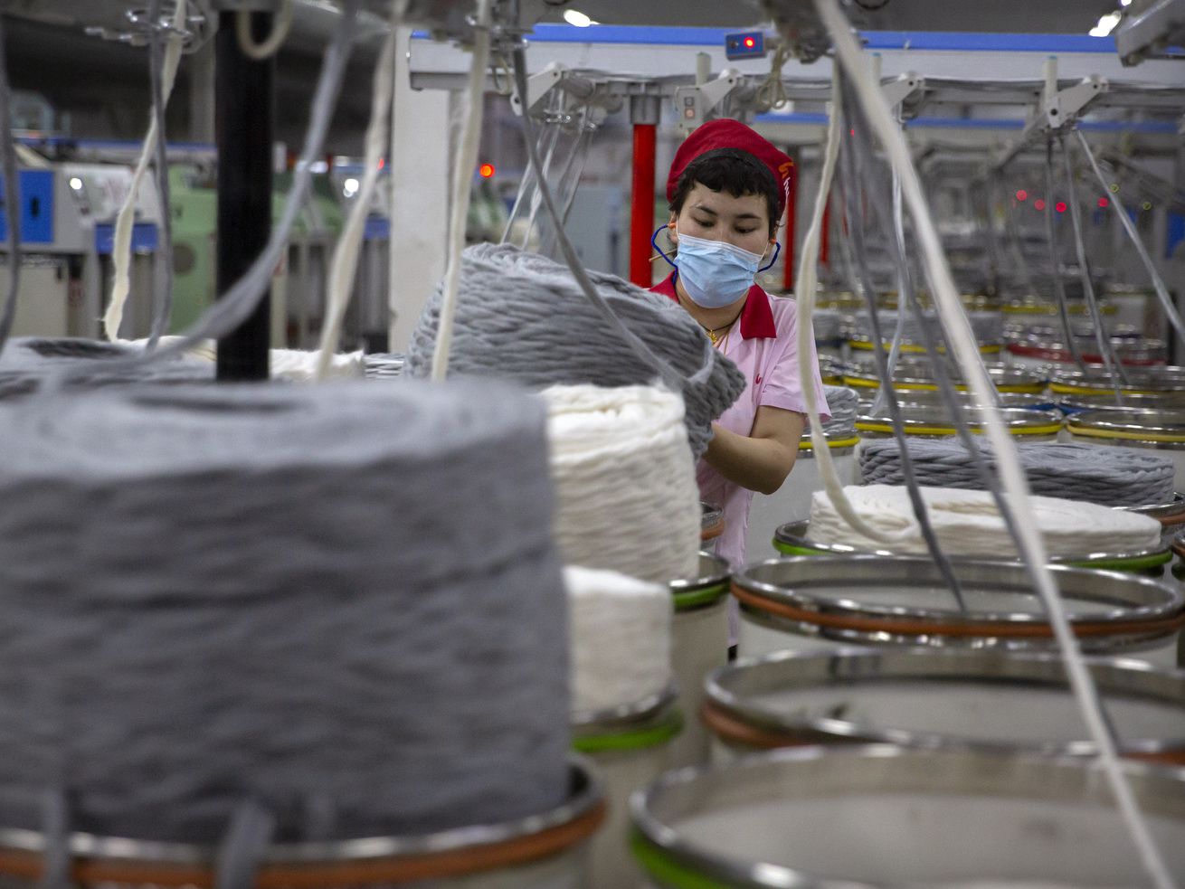 A worker gathers cotton yarn at a textile manufacturing plant in Aksu in western China’s Xinjiang Uyghur Autonomous Region, on April 20. President Joe Biden signed into law just before Christmas a bipartisan bill banning goods from China's Xinjiang region unless companies can prove they aren't made with forced labor.
