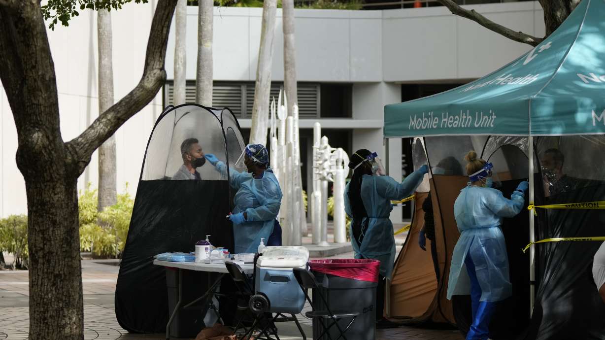 People are tested for COVID-19, at a walk-up testing site run by Nomi Health, Tuesday, in downtown Miami. New cases of COVID-19 in the U.S. have soared to the highest level on record at over 265,000 per day on average.