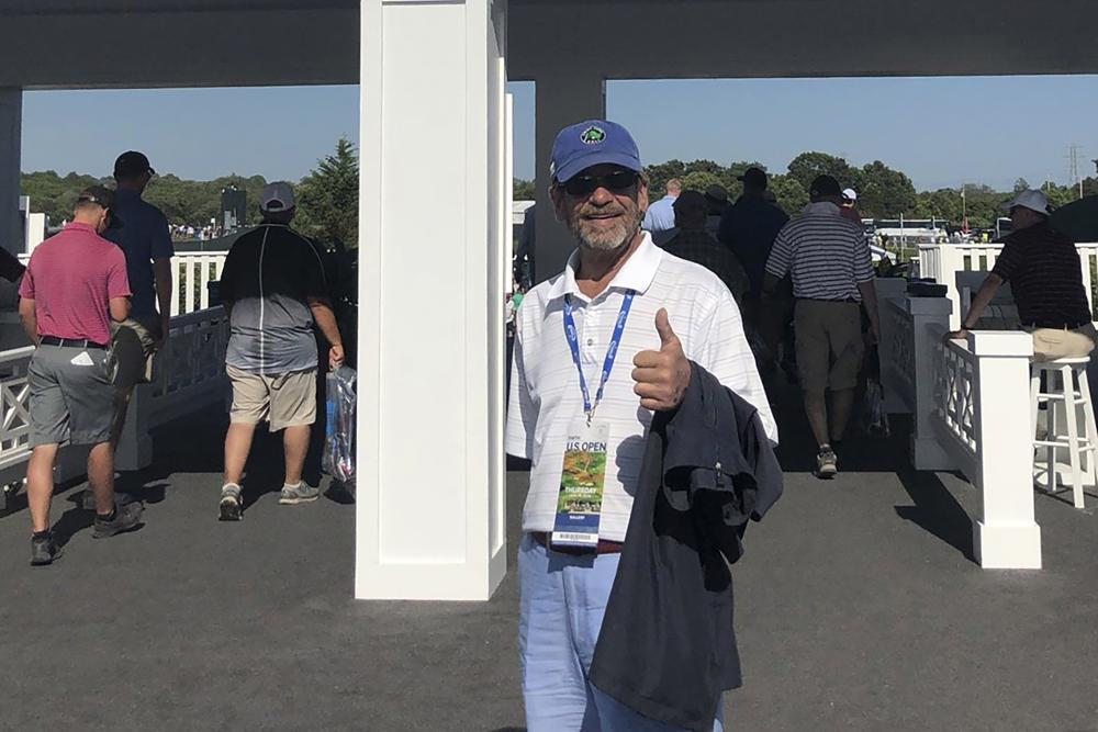 In this photo provided by Bob Van Wert, Tom Randele, whose real name according to authorities is Ted Conrad, stands for a photograph at an entrance to the 2018 U.S. Open Golf Tournament at Shinnecock Hills Golf Club, in Southampton, N.Y.
