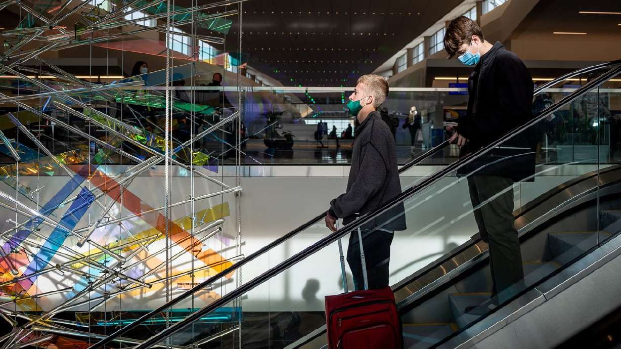Travelers ride an escalator past "The Falls,” an art installation by Gordon Huether, at Salt
Lake City International Airport in Salt Lake City on Nov. 18. New quarantine guidance may help reduce flight cancellations.