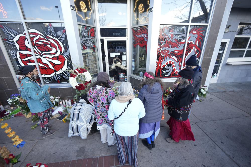 Mourners gather outside the door of a tattoo parlor along South Broadway, Tuesday in Denver, one of the scenes of a shooting spree that left six people dead—including the suspected shooter Monday evening — and left two more people wounded. 
