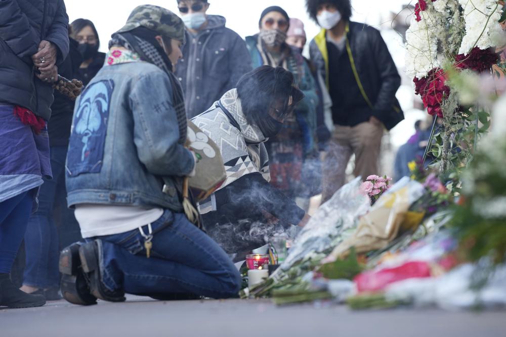 Mourners burn incense as they gather outside the door of a tattoo parlor along South Broadway Tuesday in Denver, one of the scenes of a shooting spree that left multiple people dead—including the suspected shooter Monday evening—and a few other people wounded.