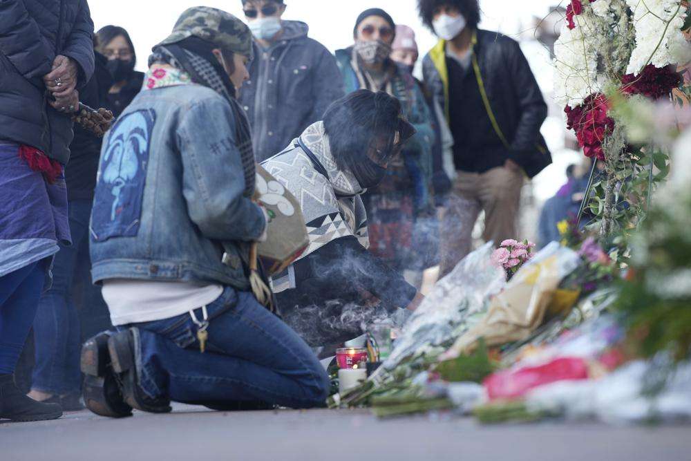 Mourners burn incense as they gather outside the door of a tattoo parlor along South Broadway Tuesday in Denver, one of the scenes of a shooting spree that left multiple people dead—including the suspected shooter Monday evening—and a few other people wounded.