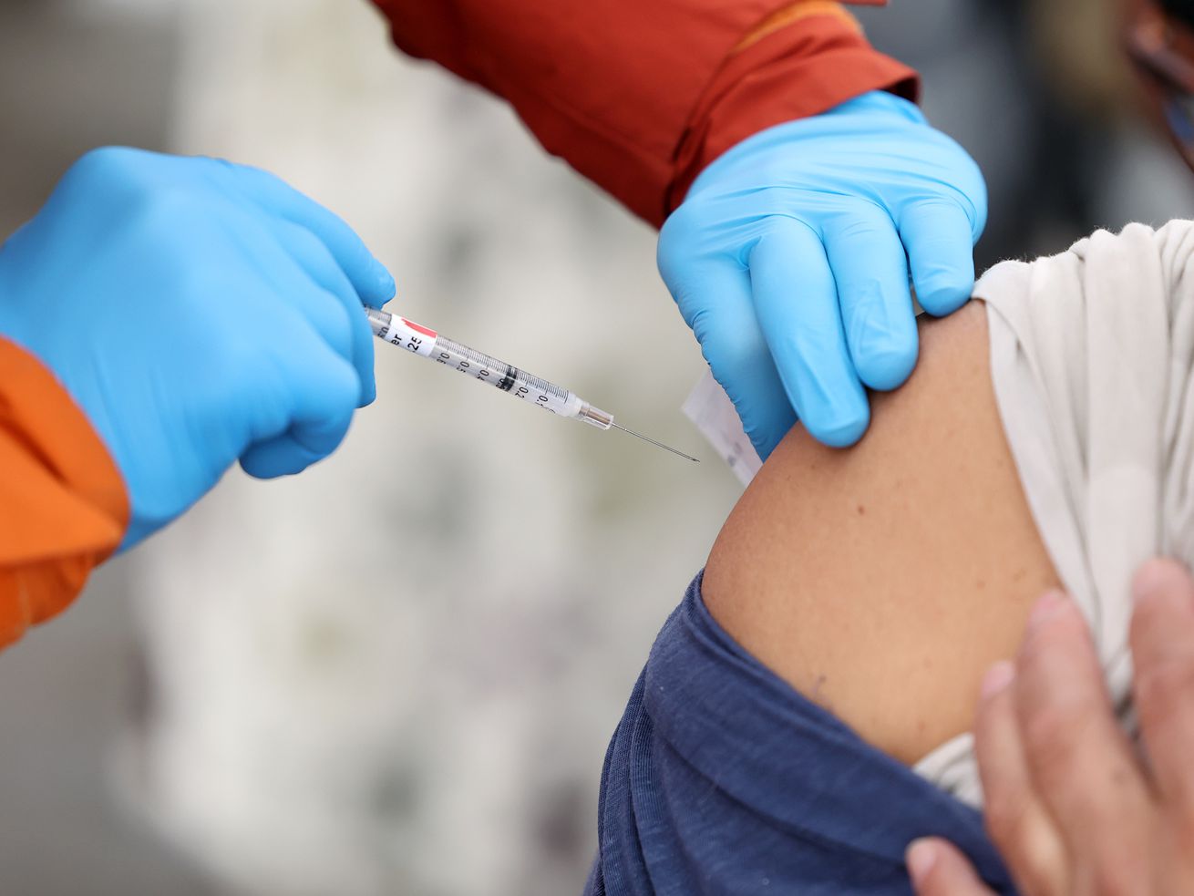 EMT Tristin Torkelson gives Luis Crespin a COVID-19 vaccination at a Salt Lake County Health Department mobile site in Salt Lake City on Dec. 29. For the third consecutive day, Utah health officials reported a record in new COVID-19 cases confirmed in a single day on Friday, with 9,469.