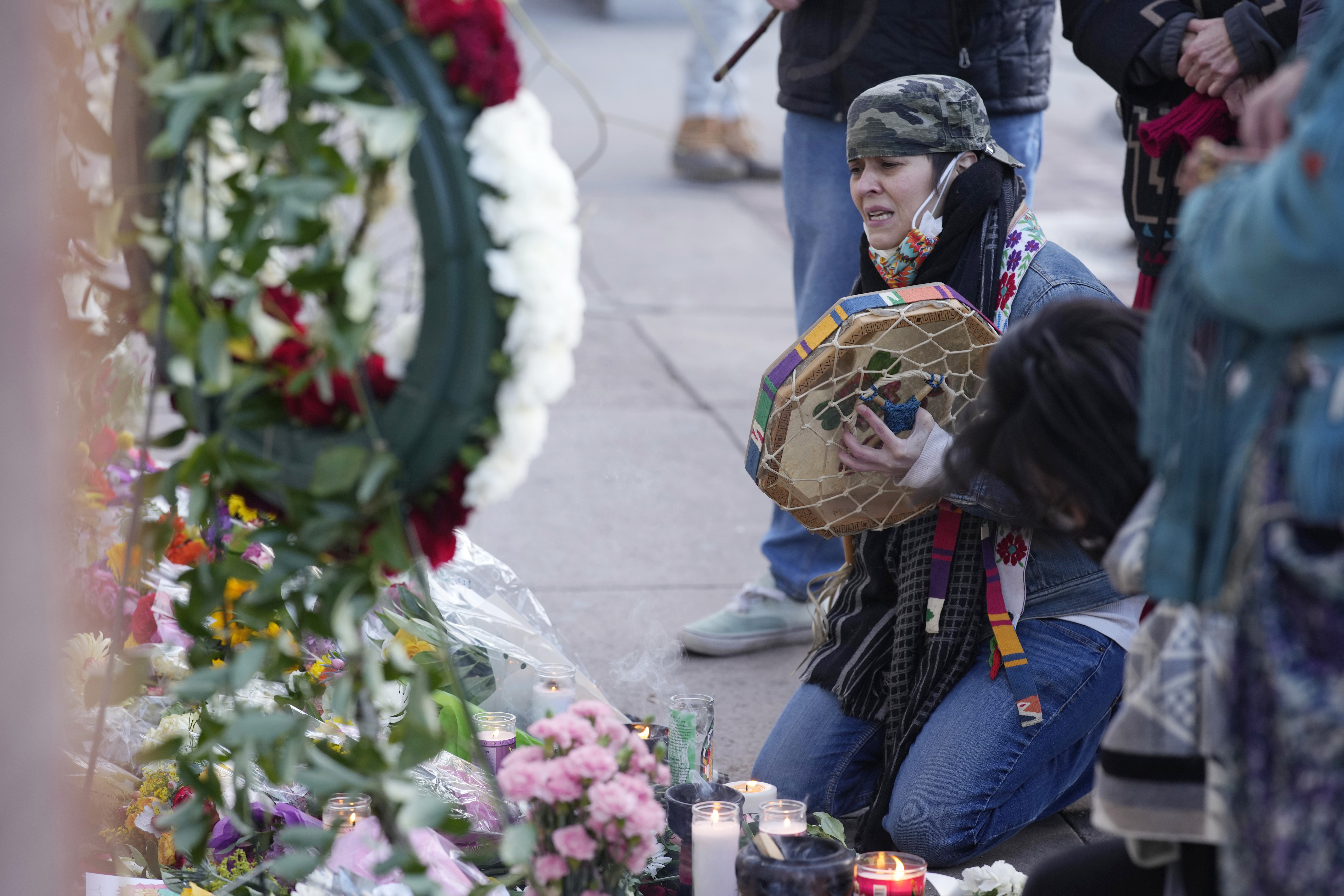 Mourners gather outside a tattoo parlor Tuesday in Denver, one of the scenes of a shooting spree that left multiple people dead. The suspect is believed to have written fictional books that described similar attacks.
