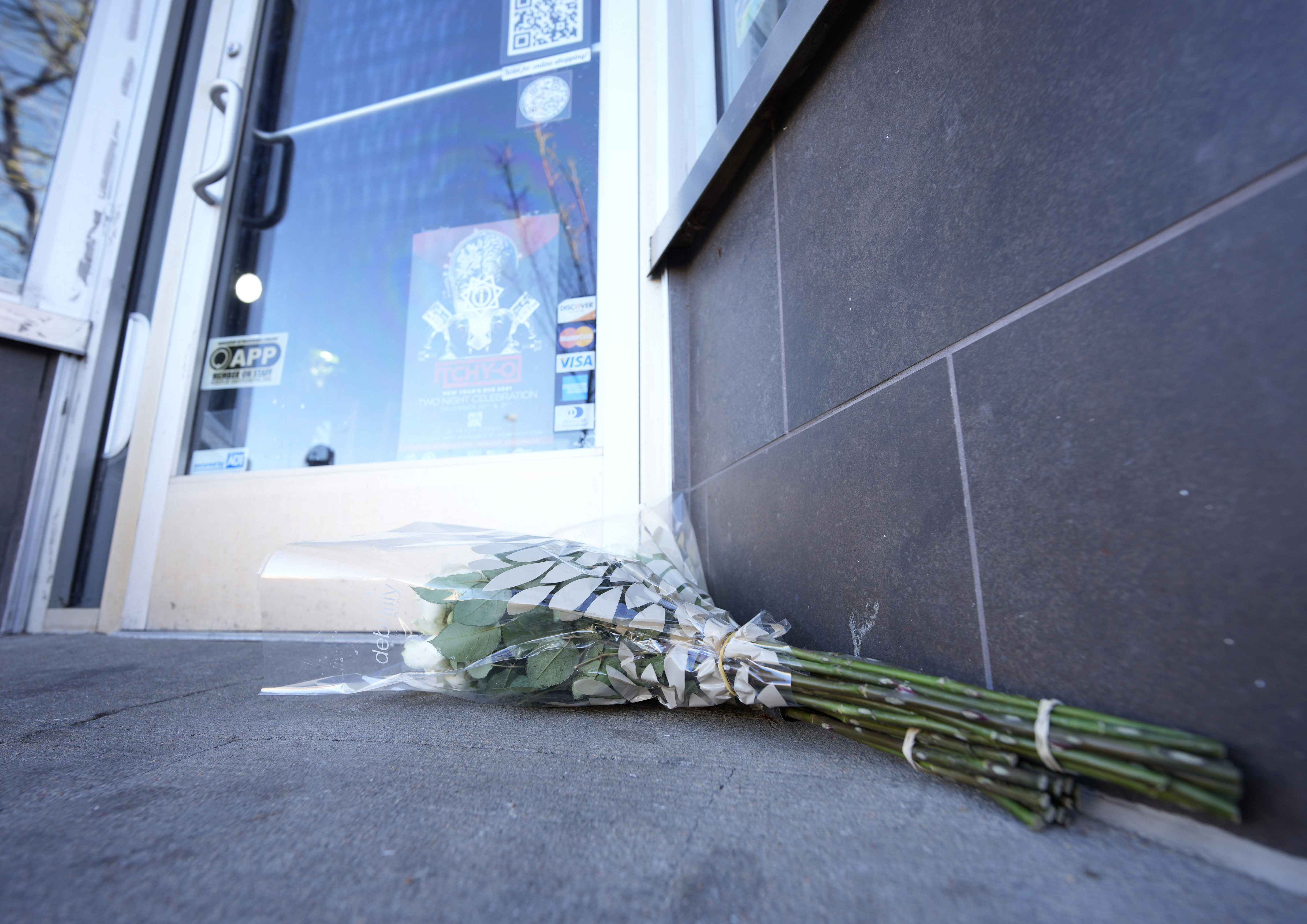 Bouquets of flowers are placed outside the door of a tattoo parlor along South Broadway Tuesday in Denver, one of the scenes of a shooting spree that left five people dead Monday evening.