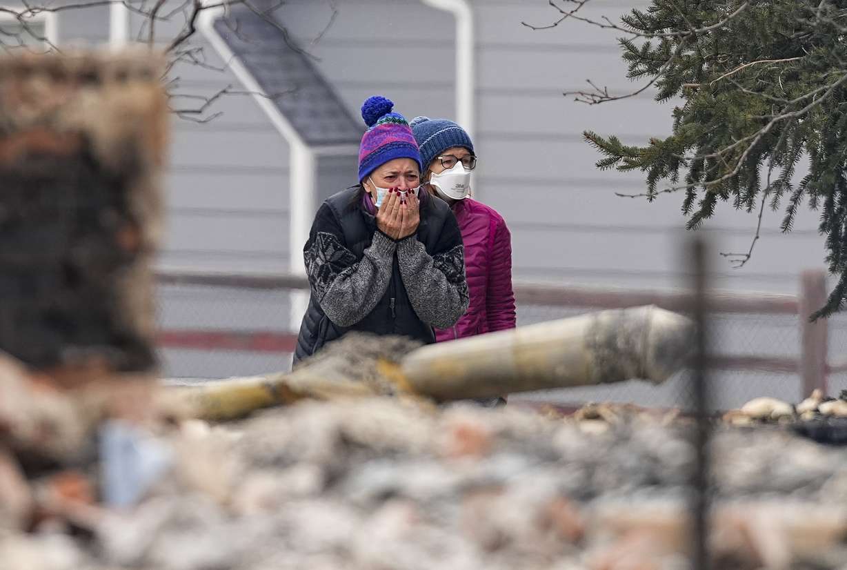 A woman cries as he sees the burned remains of a home destroyed by the Marshall Wildfire in Louisville, Colo., Friday.