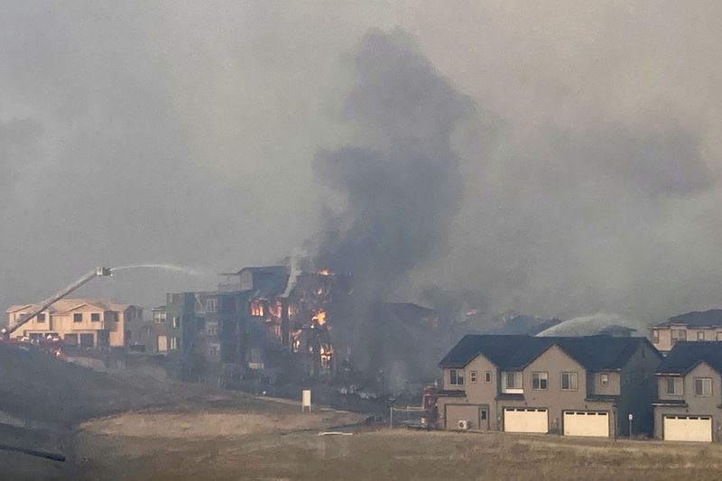 Firefighters spray water on a structure fire as a wildfire burns on Thursday, in Superior, Colo. Thousands of residents in Superior and Louisville, two communities near Denver, were ordered to evacuate Thursday because of a wind-fueled wildfire.