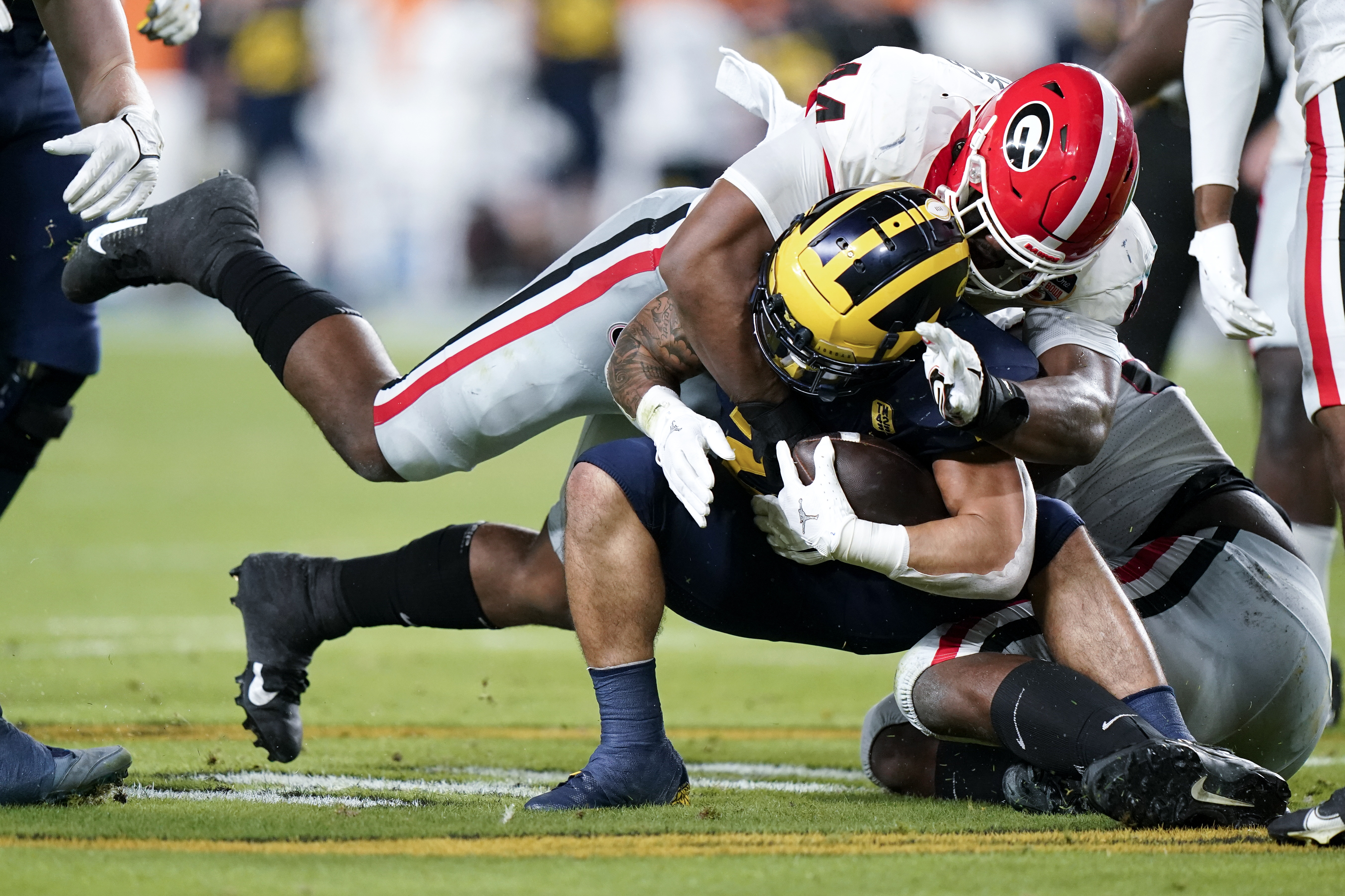Michigan running back Blake Corum is tackled by Georgia defensive lineman Travon Walker during the first half of the Orange Bowl NCAA College Football Playoff semifinal game, Friday, Dec. 31, 2021, in Miami Gardens, Fla.