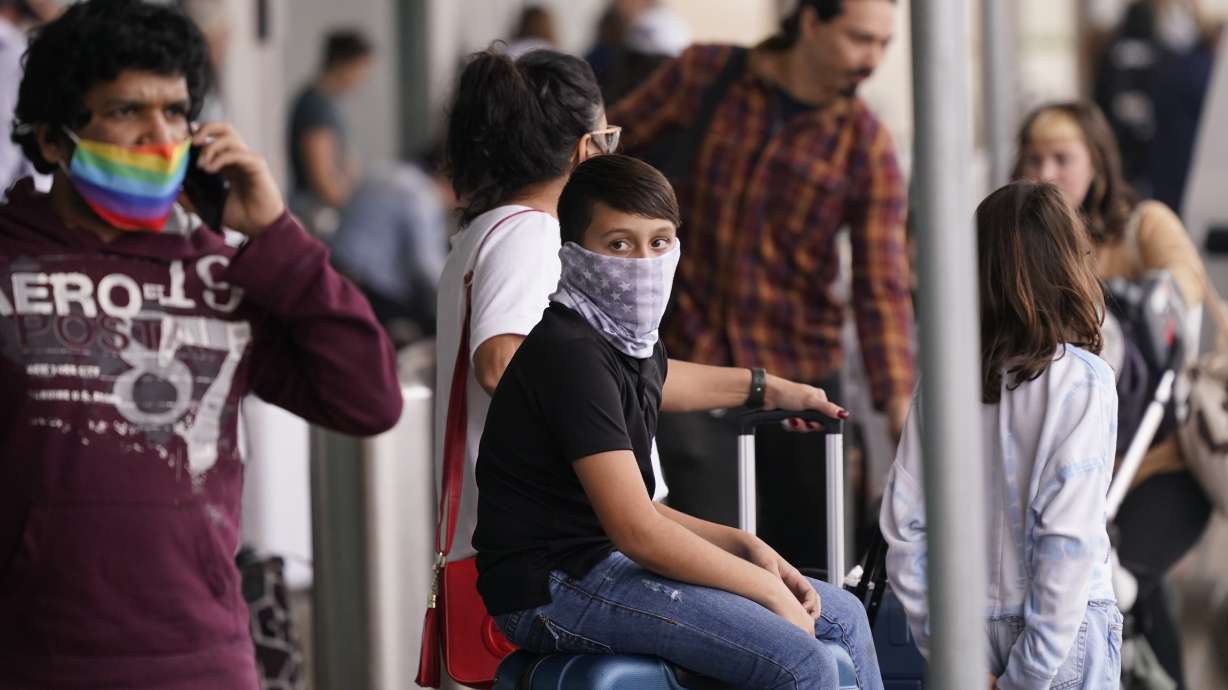 To prevent the spread of COVID-19, air travelers wear masks at Love Field in Dallas on Friday. Flight cancellations surged again on the last day of 2021, with airlines blaming wintry weather and high numbers of sickouts due to the rising number of COVID-19 infections around the country.