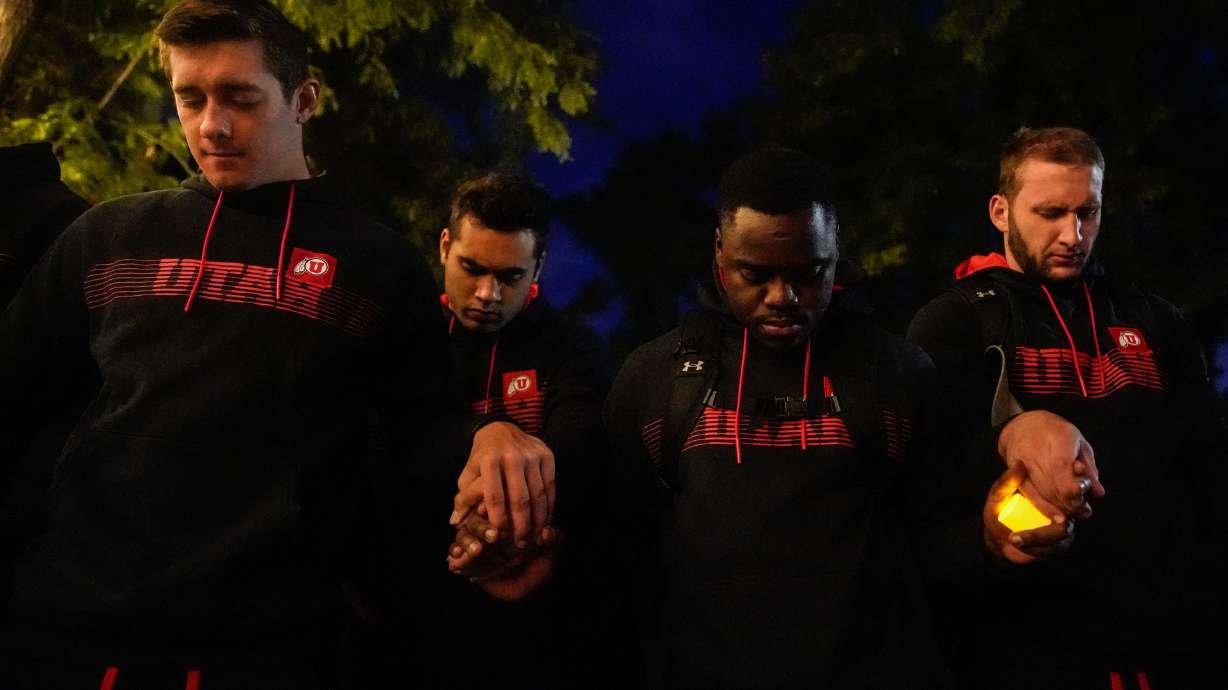 University of Utah football players hold hands as they pray during a candlelight vigil for slain football defensive back Aaron Lowe at the University of Utah on Sept. 29, 2021. He was one of 71 people who were shot to death in Utah during 2021.