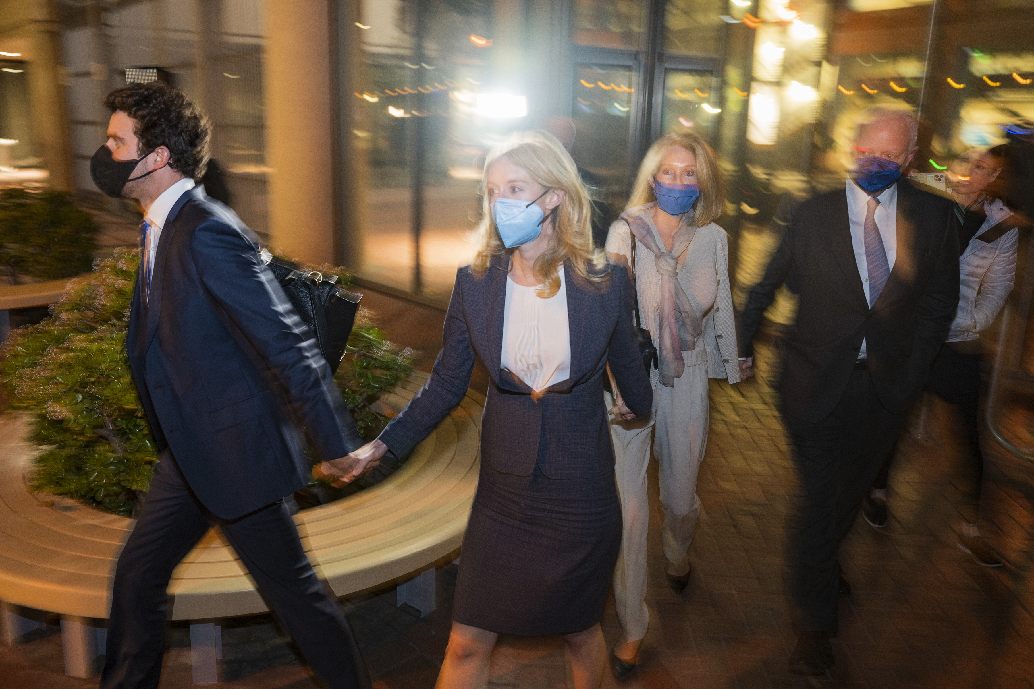Elizabeth Holmes, second from left, walks out of federal court in San Jose, Calif., on Dec. 17, 2021. Holmes was convicted on four counts of fraud and conspiracy Monday.