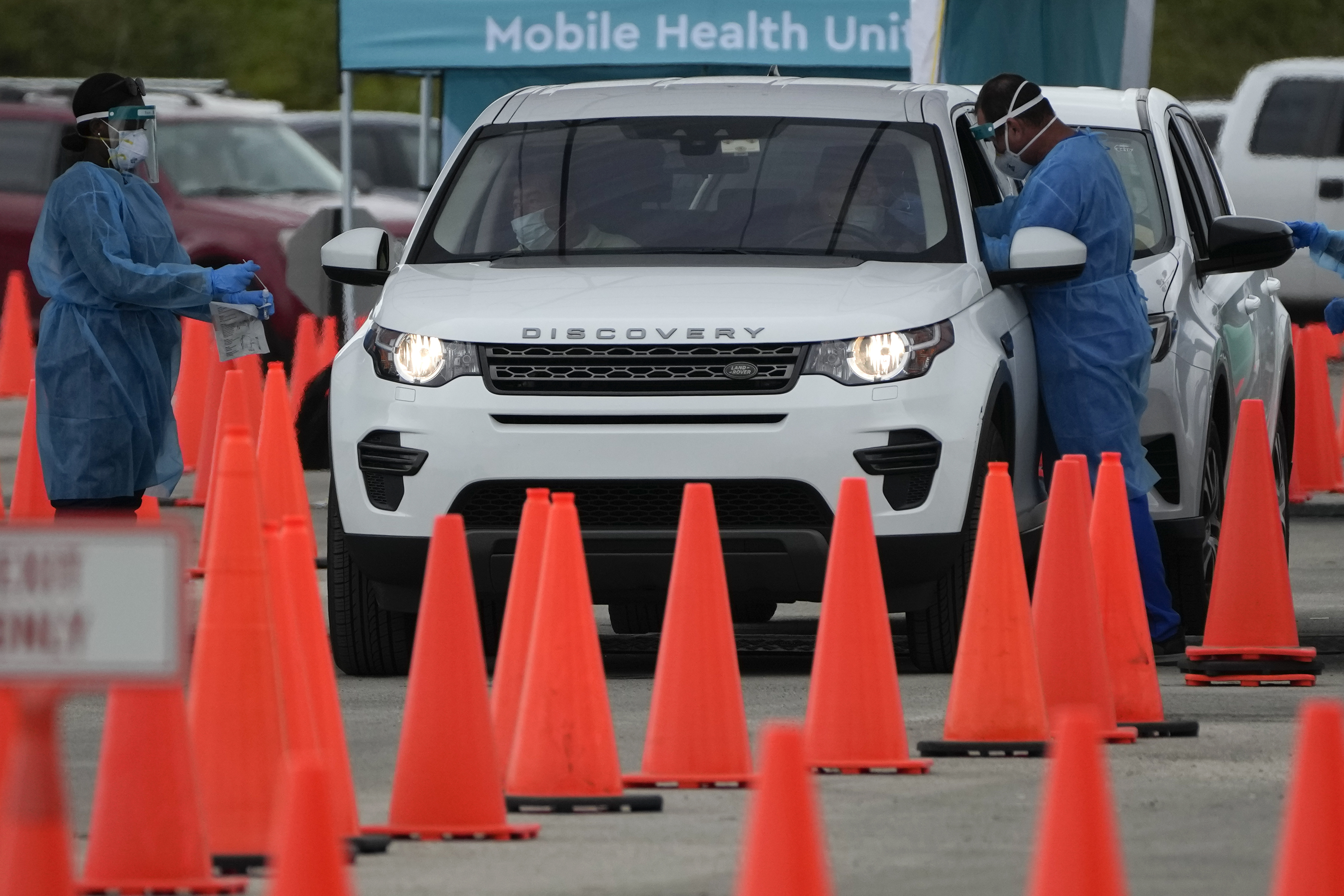 Health care workers administer nasal swabs to drivers and passengers at a drive-through COVID-19 testing site at Zoo Miami, on Jan. 3 in Miami.