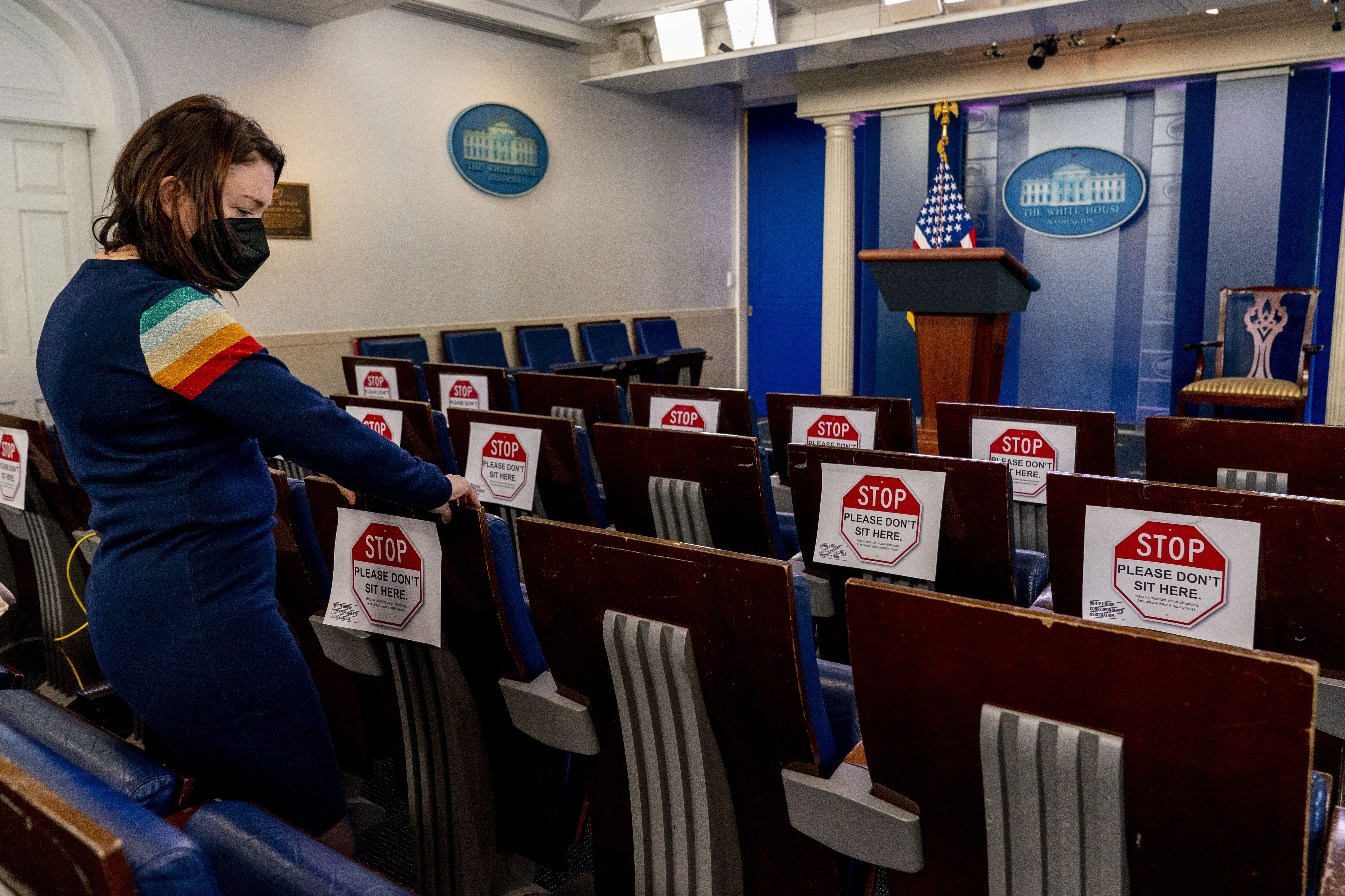White House Correspondents Association Vice President Tamara Keith tapes up signs restricting the number of reporters who can sit in the Briefing Room of the White House on Tuesday, as part of increased COVID-19 restrictions due to the omicron surge.