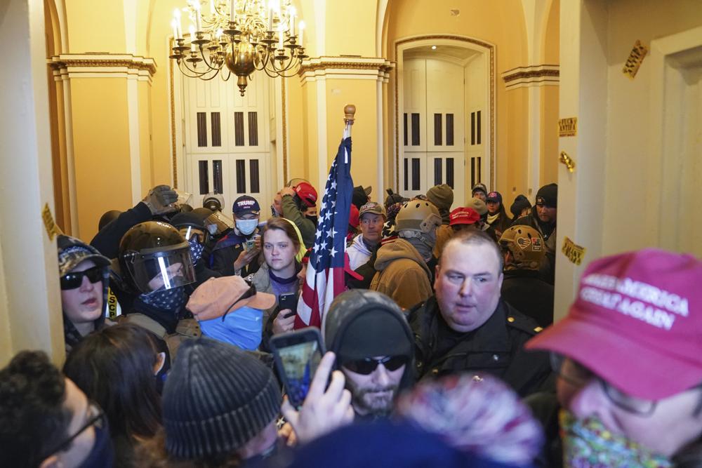 A U.S. Capitol Police officer is surrounded by rioters at a door on the East Front of the U.S. Capitol on Jan. 6, 2021, in Washington.