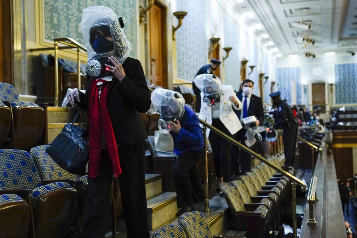 Members of Congress wear emergency gas masks as they are evacuated from the House gallery as rioters try to break into the House Chamber at the U.S. Capitol on Jan. 6, 2021, in Washington.
