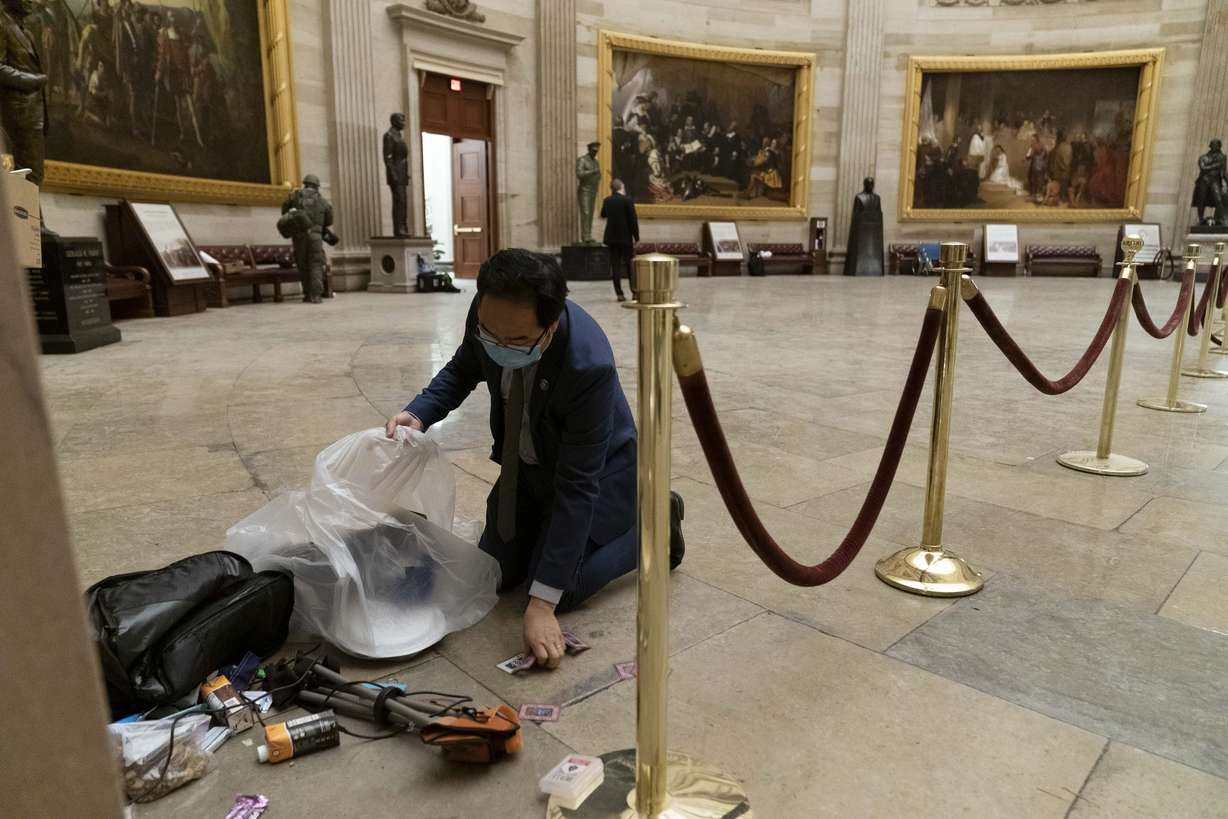 Rep. Andy Kim, D-N.J., cleans up debris and personal belongings strewn across the floor of the Rotunda in the early morning hours of Jan. 7, 2021, after rioters stormed the Capitol in Washington.