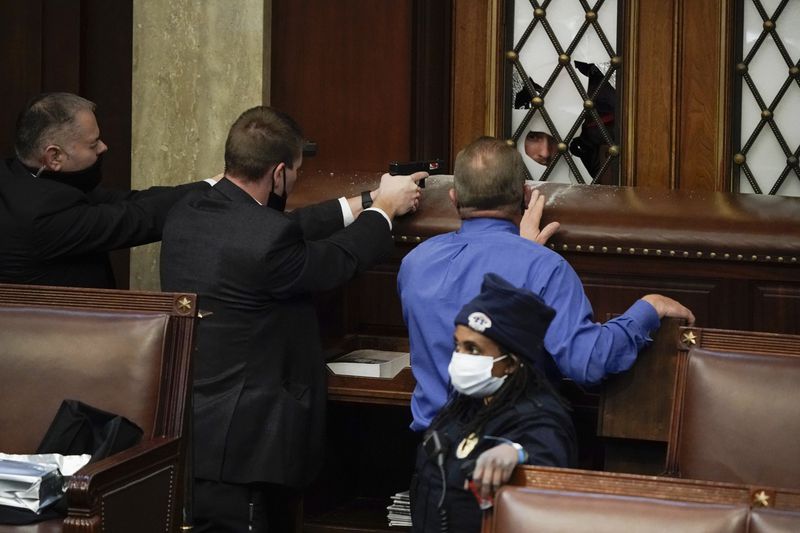 Police with guns drawn watch as rioters try to break
into the House chamber at the U.S. Capitol on Wednesday, Jan. 6,
2021, in Washington.