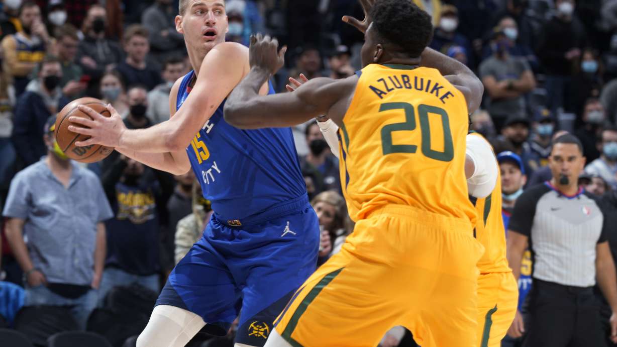 Denver Nuggets center Nikola Jokic, left, looks to pass the ball as Utah Jazz center Udoka Azubuike defends during the first half of an NBA basketball game Wednesday, Jan. 5, 2022, in Denver.