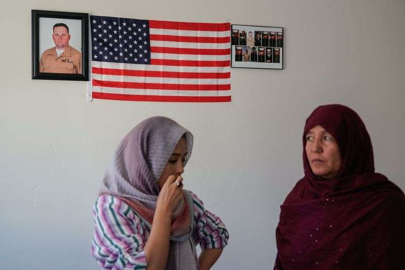 Afghan refugee Shazia Kakaie left, talks to her mother, Hawa Sultani, in front of a framed picture of slain U.S. Marines Staff Sgt. Taylor Hoover at their house in North Salt Lake on Tuesday, Nov. 23, 2021. Hoover, who was from Utah, was one of the 13 American service members killed in a bombing at the airport in Kabul, Afghanistan.