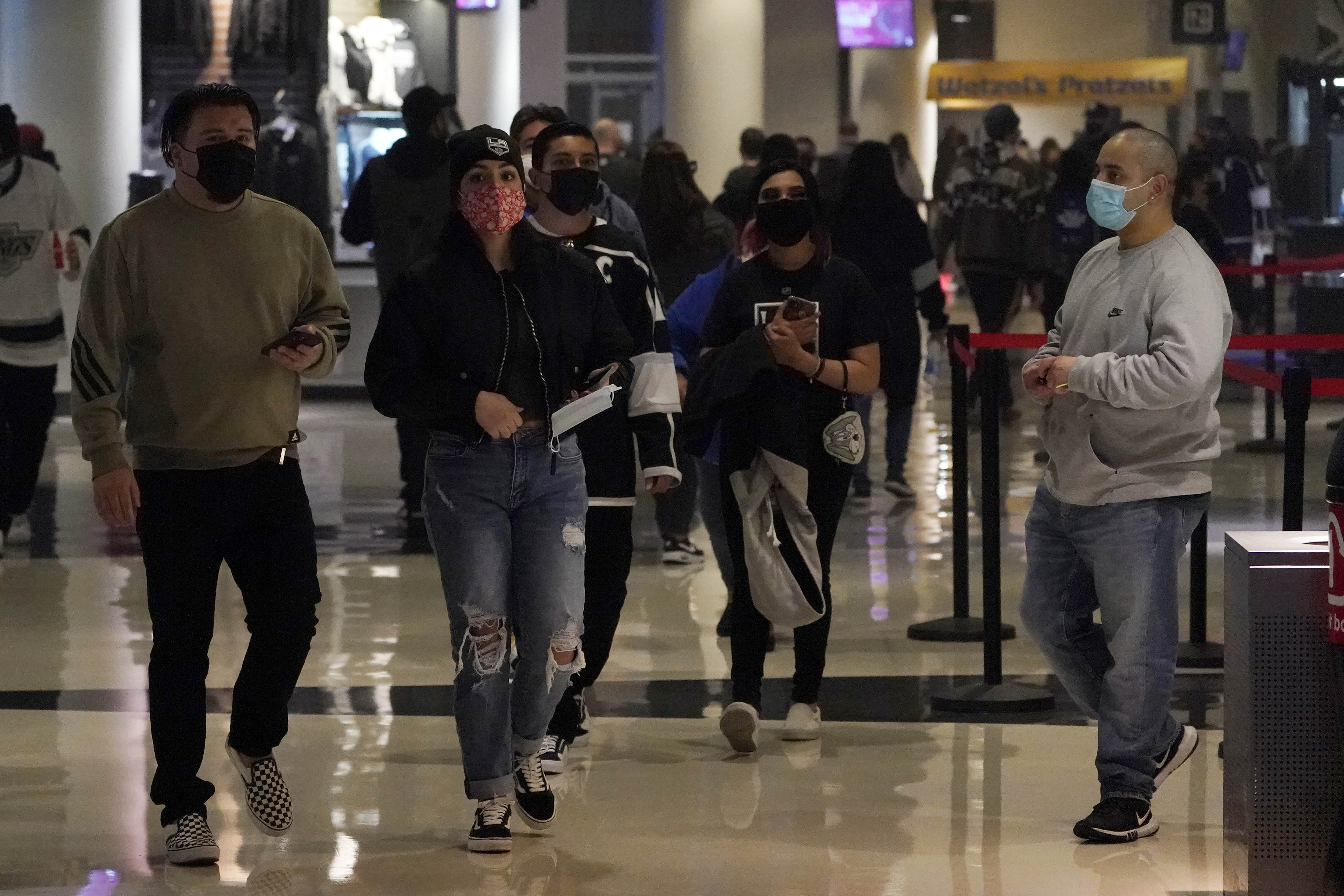 Fans wear masks as they walk inside crypto.com Arena before an NHL hockey game between the Los Angeles Kings and the Nashville Predators Thursday, in Los Angeles. 