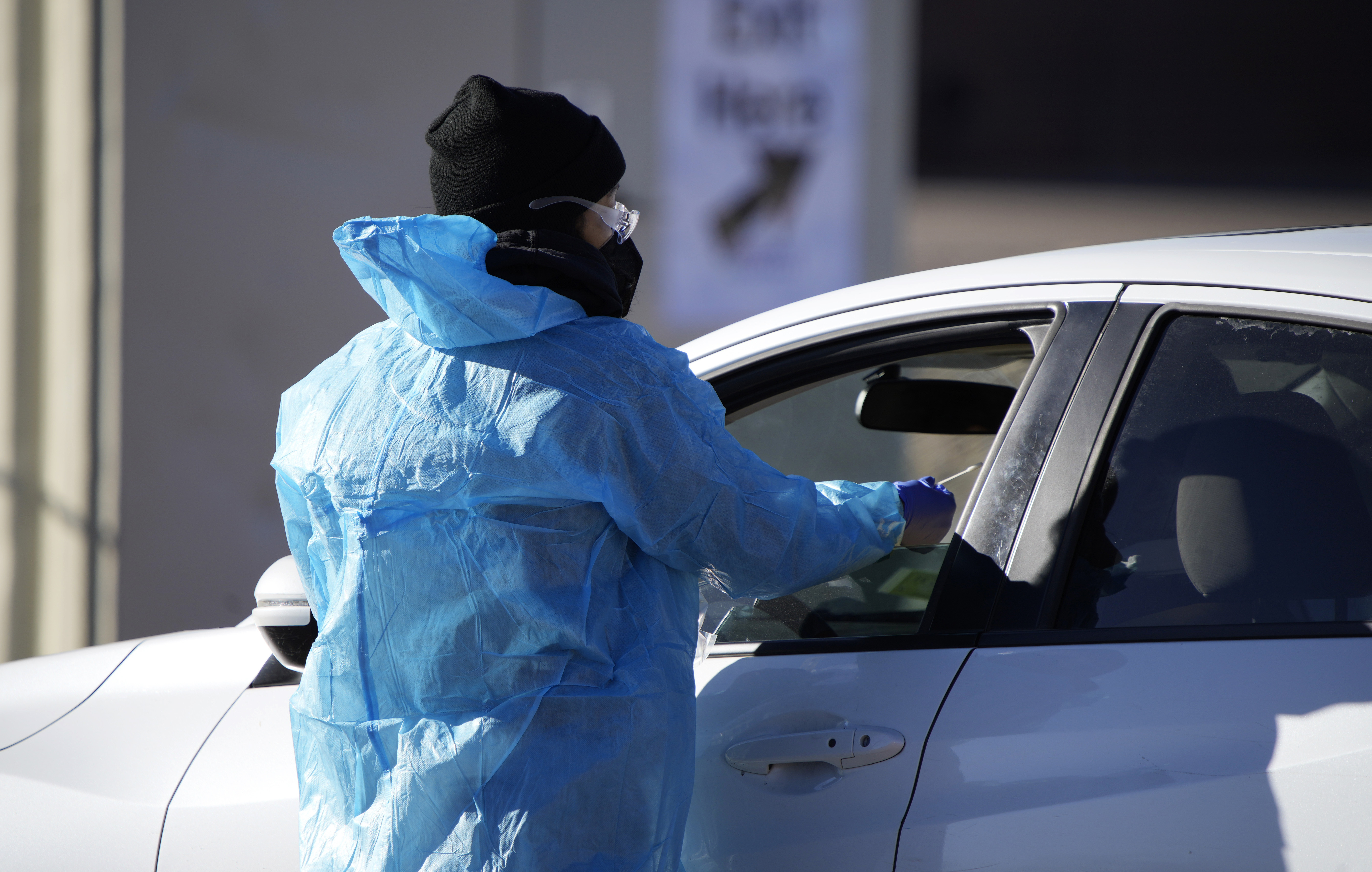 A medical technician performs a nasal swab test on a motorist queued up in a line at a COVID-19 testing site near All City Stadium Dec. 30, 2021, in southeast Denver.