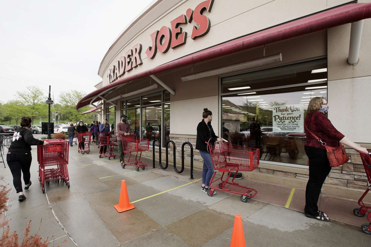 Customers observe social distancing as they wait to be allowed to shop at a Trader Joe's supermarket in Omaha, Neb., May 7, 2020.