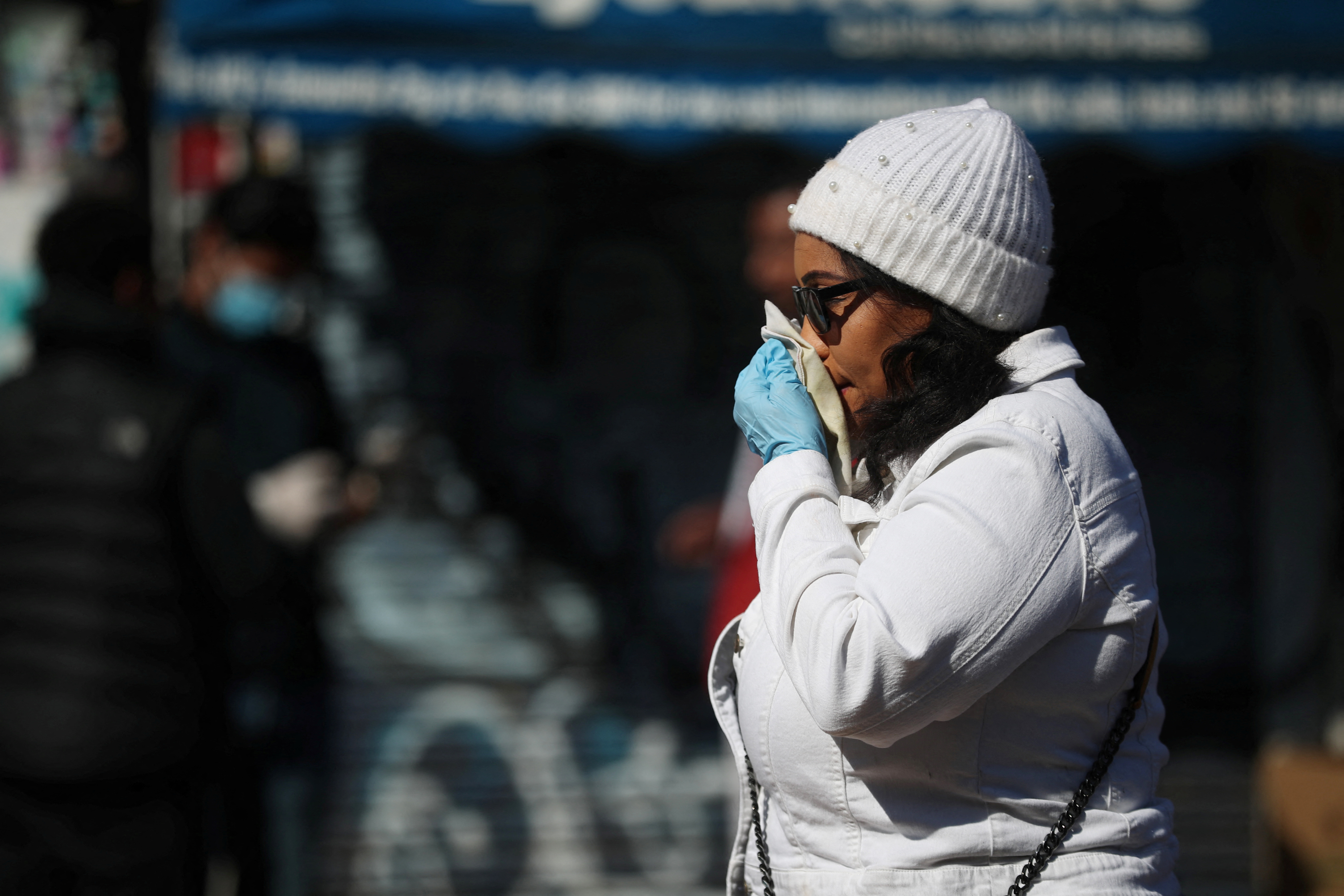A woman blows her nose in East London on April 14, 2020. High levels of T cells from common cold coronaviruses can provide protection against COVID-19, a study published on Monday has found.