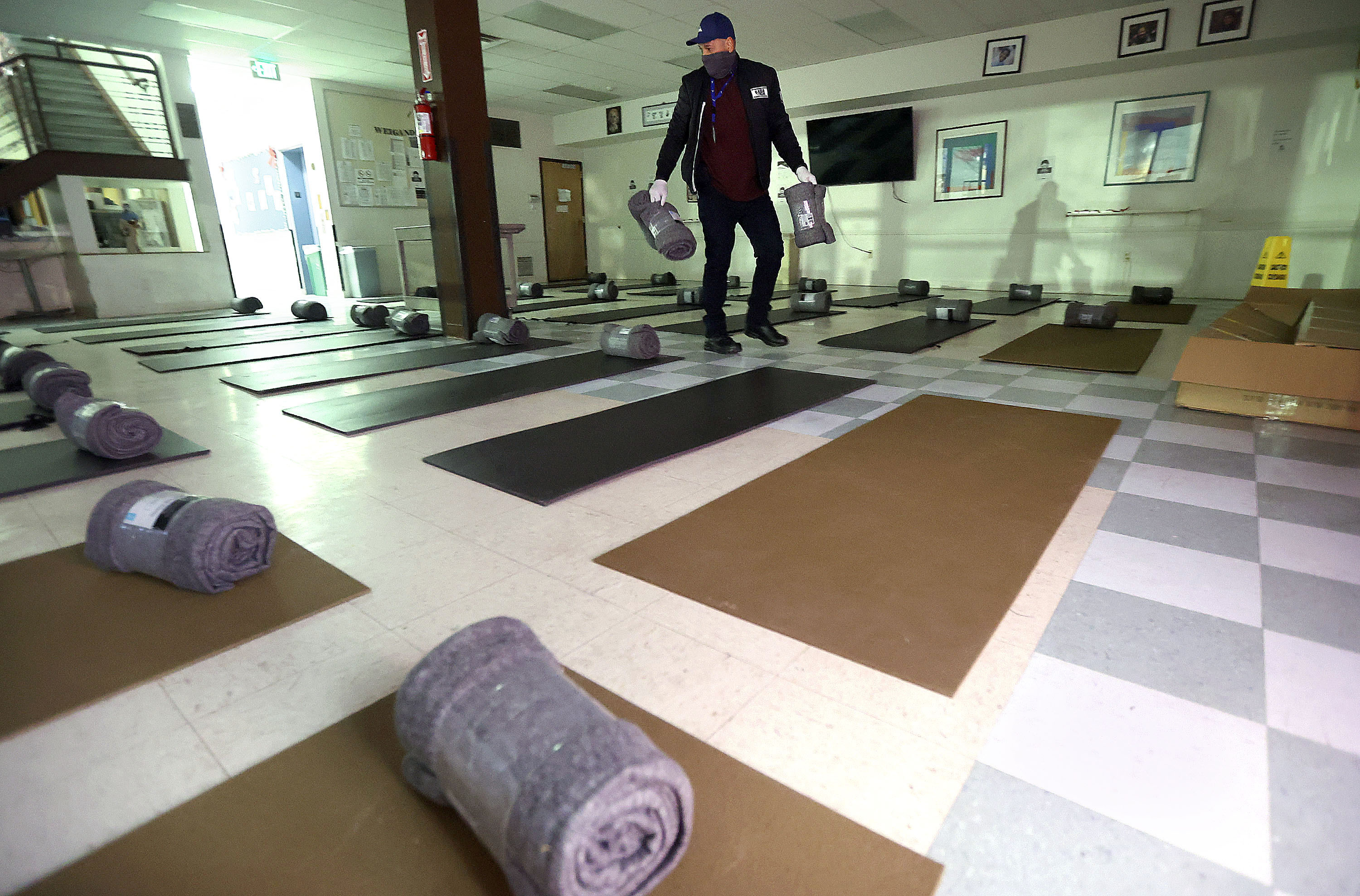 Luis Perez, Volunteers of America shift lead, sets up overflow beds for the homeless in the Weigand Center for the Weigand Winter Overflow in Salt Lake City on Monday.