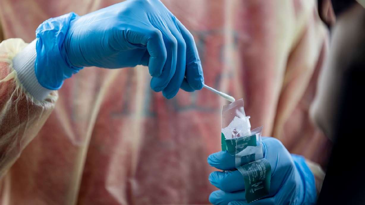 Health care worker Bob Ekoh administers a COVID-19 test at City Hall in Herriman on Thursday. Utah again smashed its record counts for new COVID-19 cases on Thursday as health officials reported 12,990.