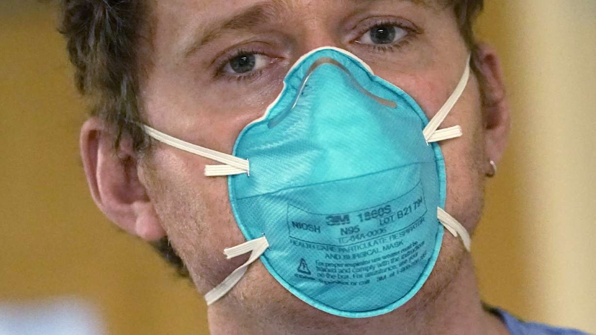 Registered nurse Scott McGieson wears an N95 mask as he walks out of a patient's room in the acute care unit of Harborview Medical Center, Friday, in Seattle.