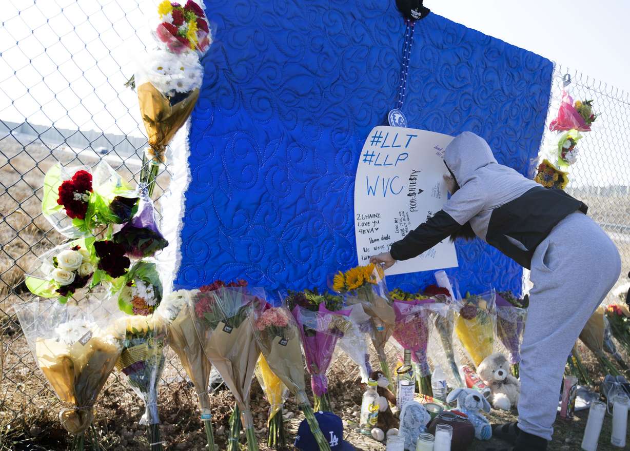Friends and family members of 15-year-old Paul Tahi and 14-year-old Tivani Lopati build a memorial in their honor in West Valley on Friday. The two teenagers were shot and killed on a sidewalk Thursday morning and another teen, also 15, was shot and critically injured.