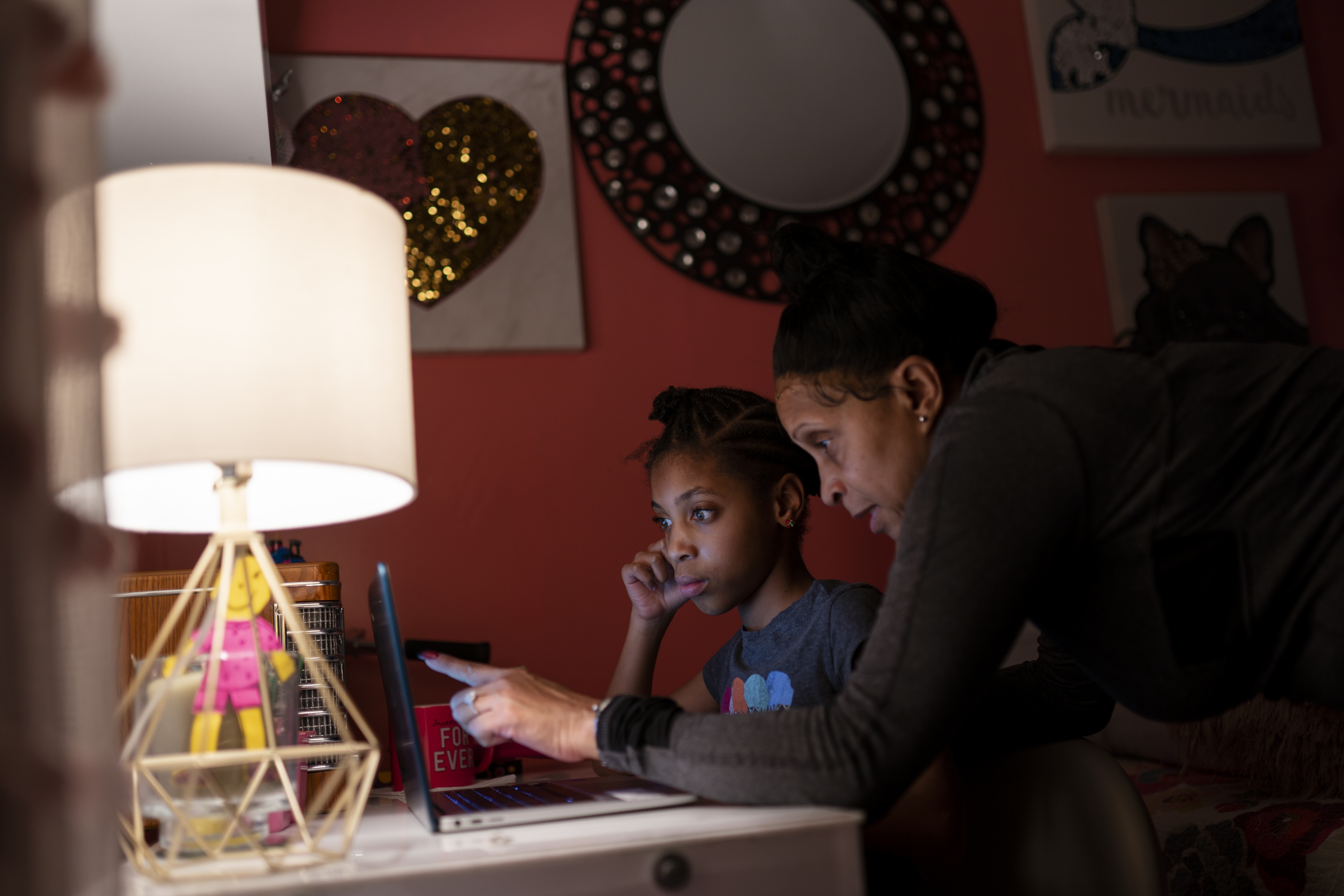 Abigail Schneider, 8, center, completes a level of her learning game with her mother April in her bedroom, Wednesday, Dec. 8, 2021, in the Brooklyn borough of New York. As more families pivot back to remote learning, reliable, consistent access to devices and home internet remains elusive for many.