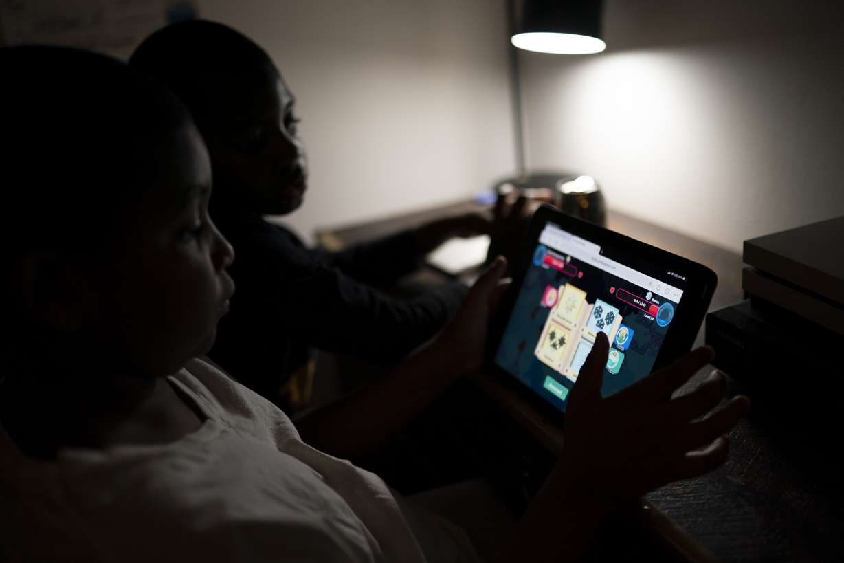 Isaiah Schneider, 9, left, and his brother Adam, 7, complete a level on their learning game played on a tablet computer, in their bedroom, Wednesday, Dec. 8, 2021, in the Brooklyn borough of New York.