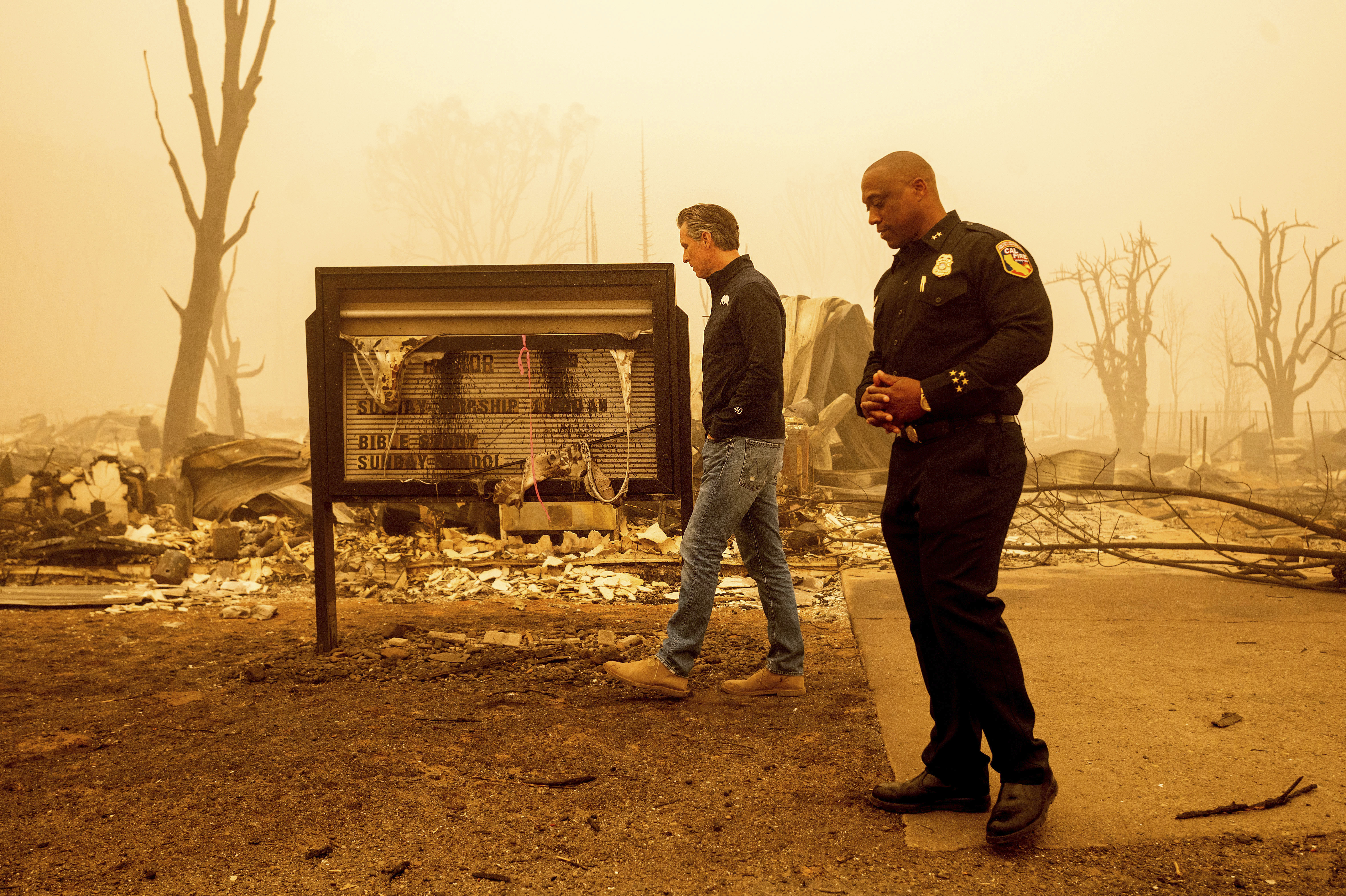 California Gov. Gavin Newsom examines a church marquee while visiting Greenville, which suffered extensive structure loss during the Dixie Fire, on Aug. 7, 2021, in Plumas County, Calif. Some governors want to spend some of their budget windfall on projects aimed at slowing climate change.
