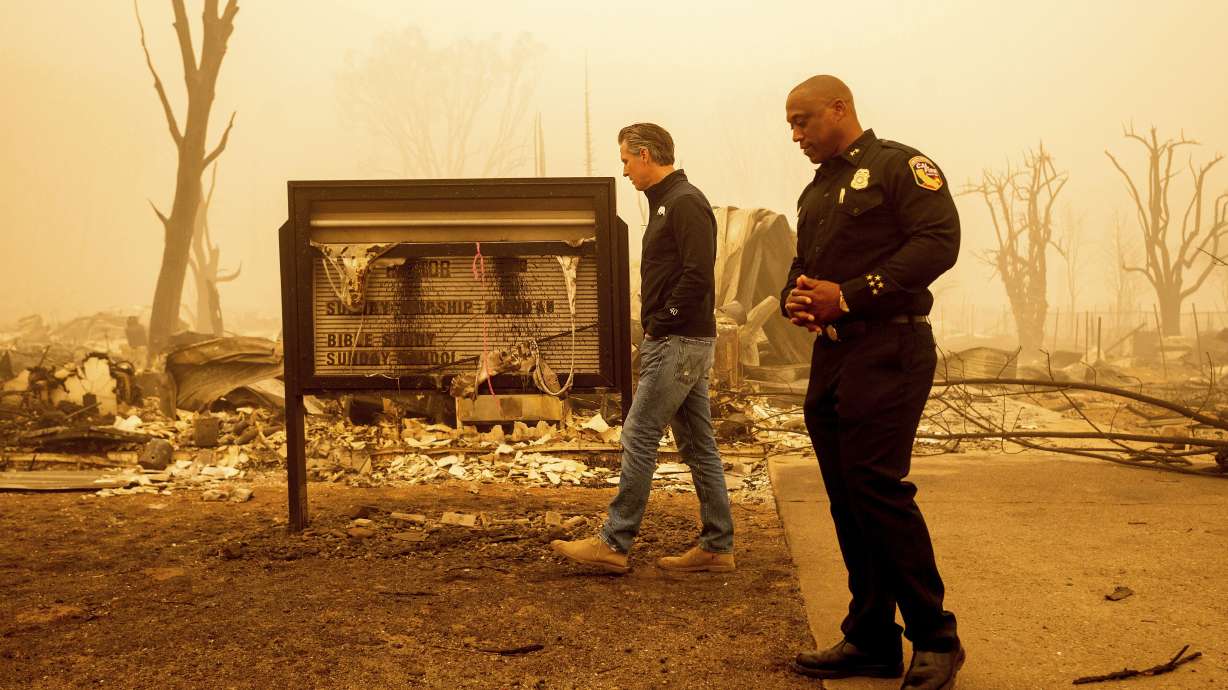 California Gov. Gavin Newsom examines a church marquee while visiting Greenville, which suffered extensive structure loss during the Dixie Fire, on Aug. 7, 2021, in Plumas County, Calif. Some governors want to spend some of their budget windfall on projects aimed at slowing climate change.