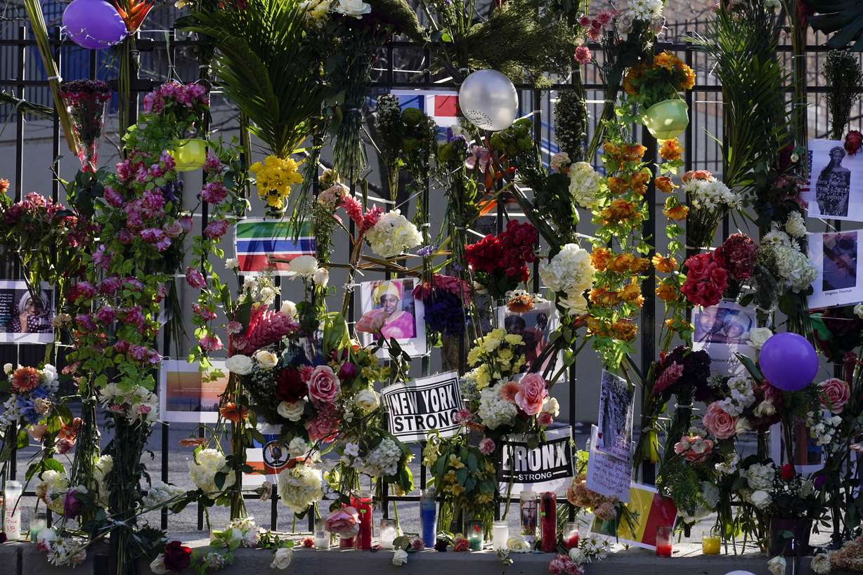 A memorial for the victims of an apartment building fire is displayed in front of the building in New York, Friday.
