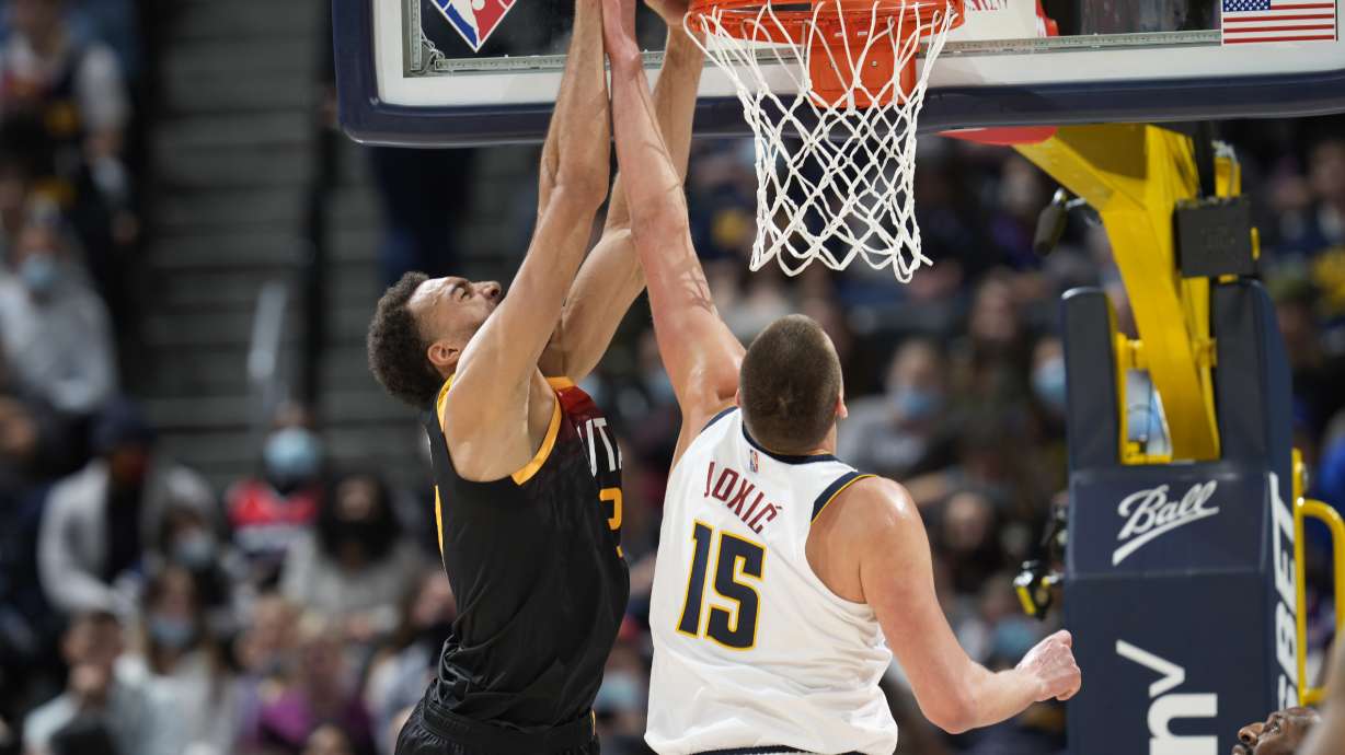 Utah Jazz center Rudy Gobert, left, dunks as Denver Nuggets center Nikola Jokic defends in the first half of an NBA basketball game Sunday, Jan. 16, 2022, in Denver.