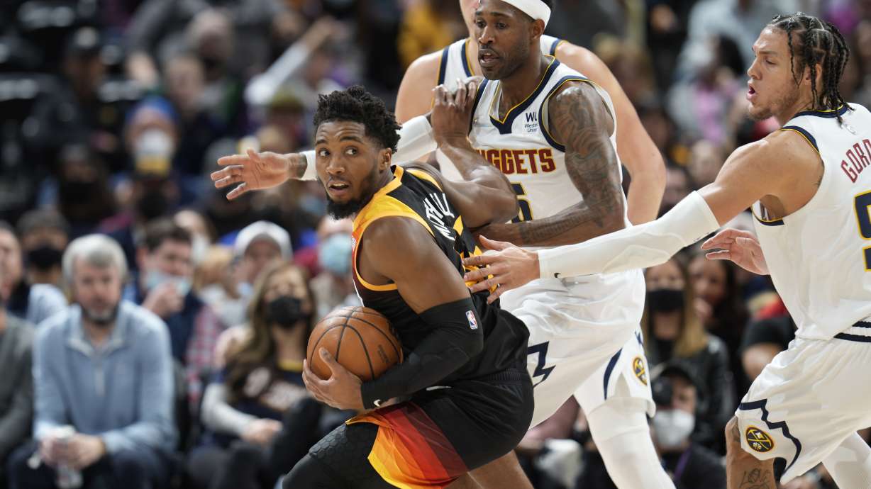 Utah Jazz guard Donovan Mitchell, left, is trapped with the ball as Denver Nuggets forwards Will Barton, center, and Aaron Gordon defend in the first half of an NBA basketball game Sunday Jan. 16, 2022, in Denver.